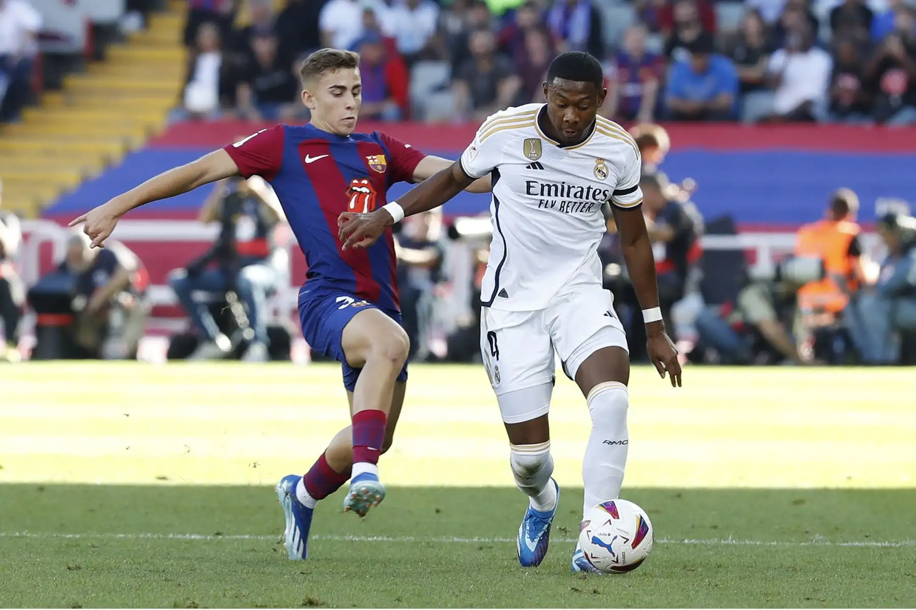 El centrocampista del FC Barcelona Fermín López disputa una posesión ante David Alaba, defensa austriaco del Real Madrid durante el partido de LaLiga que enfrenta al FC Barcelona y al Real Madrid este sábado en el Estadio Olímpico Lluís Companys de Barcelona. ANDINA/EFE
