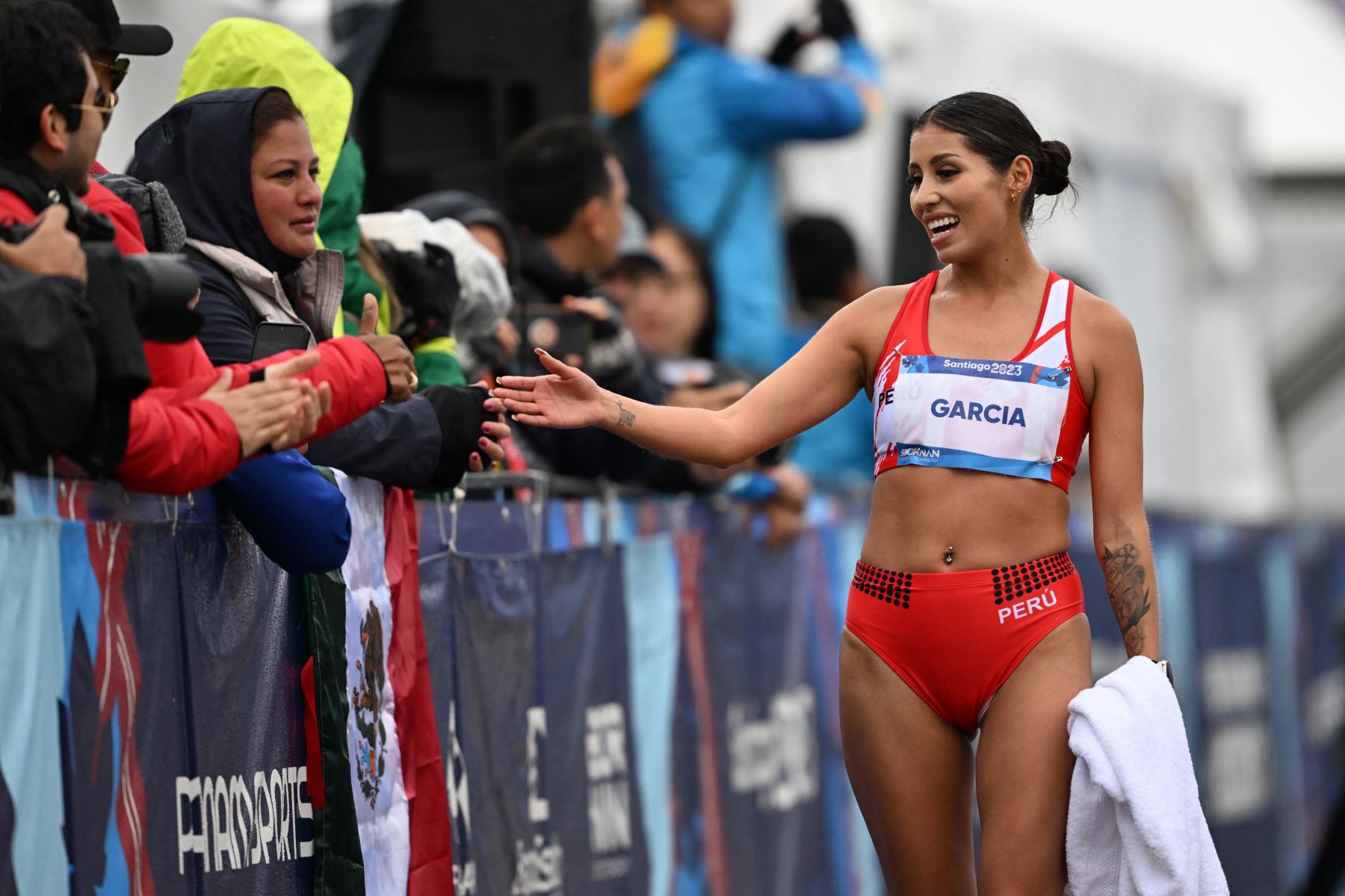 La peruana Gabriela Kimberly García León saluda a los espectadores después de llegar en primer lugar en la carrera de atletismo femenino de 20 km de marcha durante los Juegos Panamericanos Santiago 2023 en Santiago, el 29 de octubre de 2023. Foto: AFP