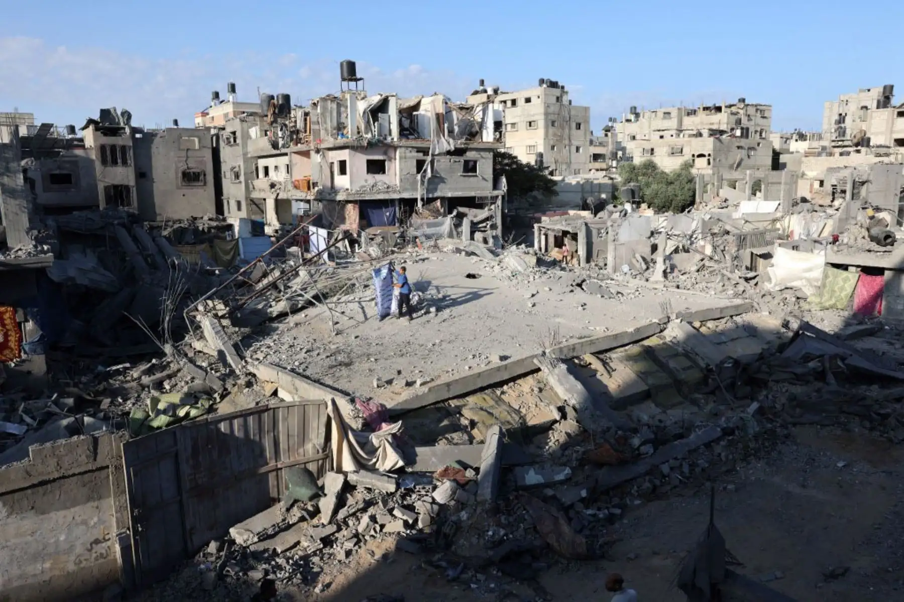 Palestinos pasan junto a una casa y un vehículo destruidos el día después de un ataque aéreo israelí contra el campo de refugiados de Nuseirat, en el centro de la Franja de Gaza. Foto: AFP