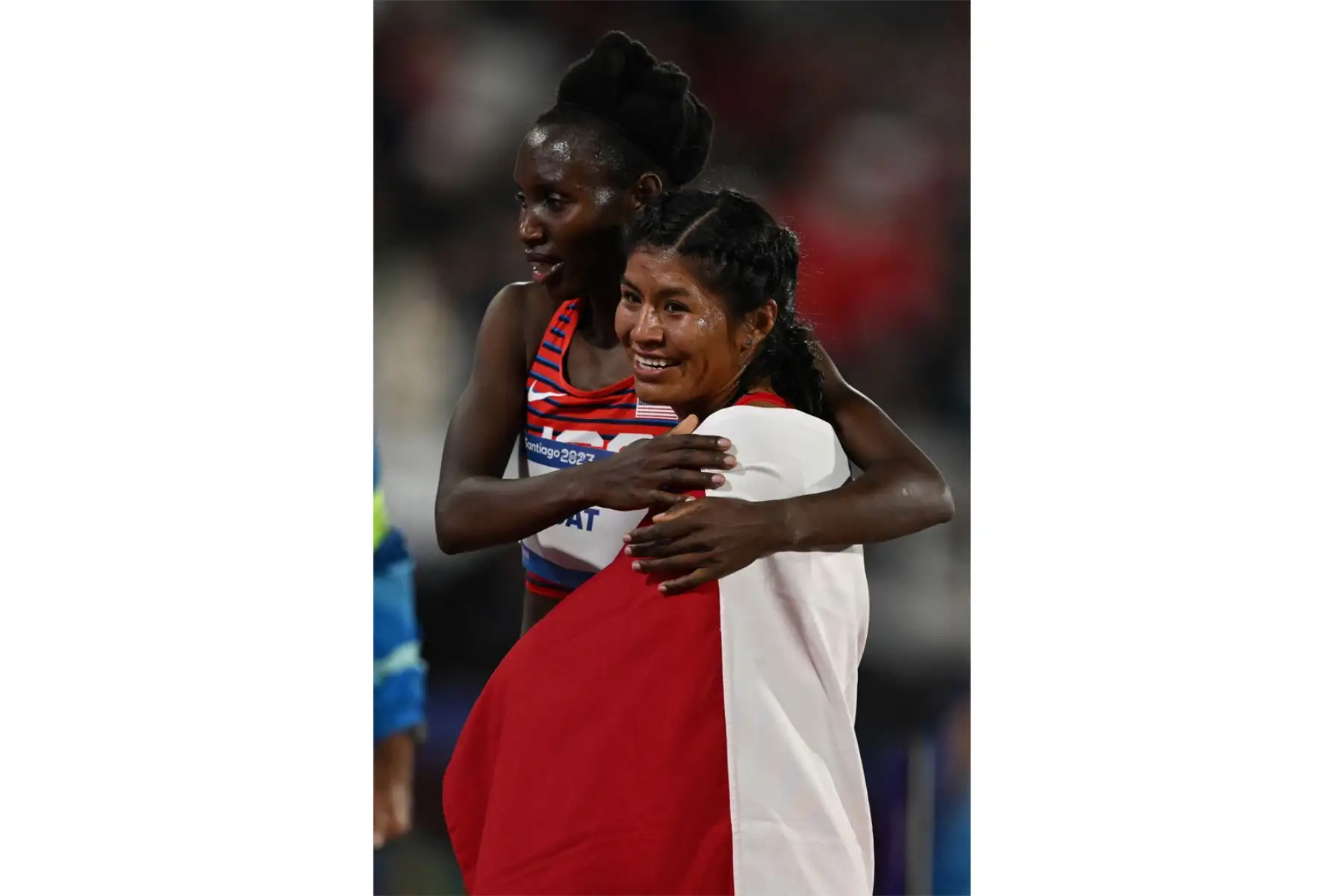La peruana Luz Mery Rojas Llanco  es recibida por la estadounidense Ednah Kurgat, tercera clasificadora, después de ganar la final femenina de 10.000 m de los Juegos Panamericanos Santiago 2023 en el Estadio Nacional de Santiago. Foto: ANDINA/AFP