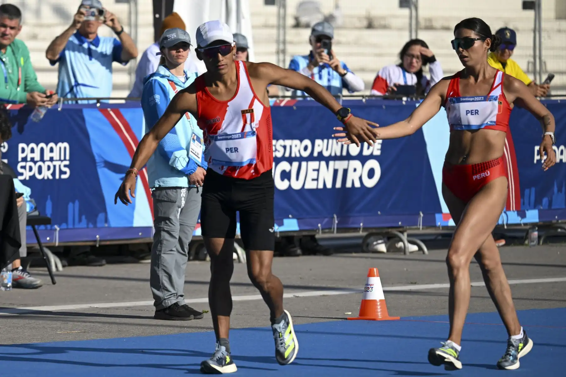 El peruano César Augusto Rodríguez Diburga reemplaza a Kimberly García durante la final de relevos mixtos de caminata de maratón de los Juegos Panamericanos Santiago 2023 en la Explanada Campo de Marte en Santiago el 4 de noviembre de 2023. Foto: ANDINA/ AFP
