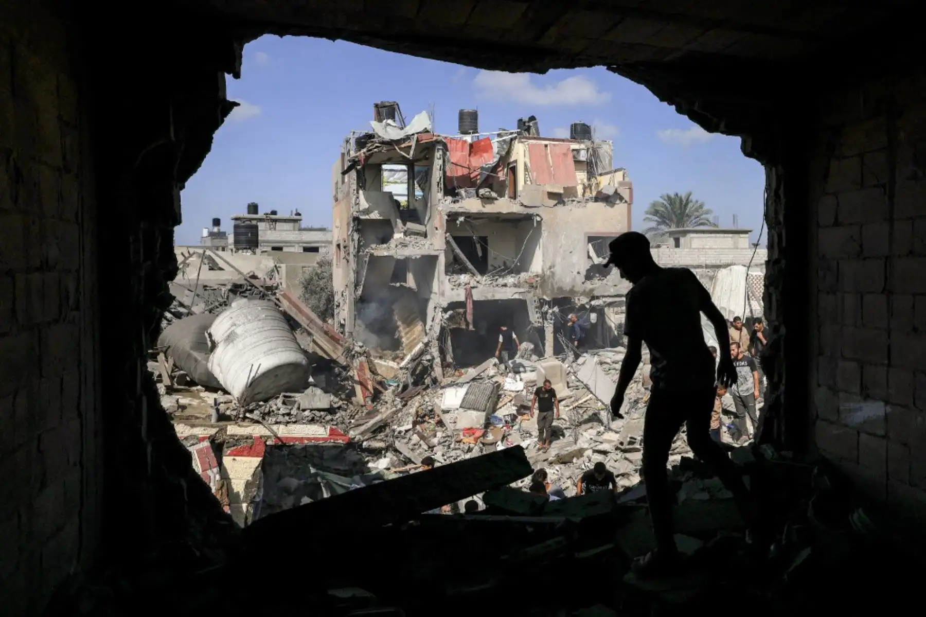Un miembro de la defensa civil palestina rocía un edificio con una manguera para apagar un incendio en un edificio derrumbado después del bombardeo israelí en Khan Yunis, en el sur de la Franja. Foto: AFP