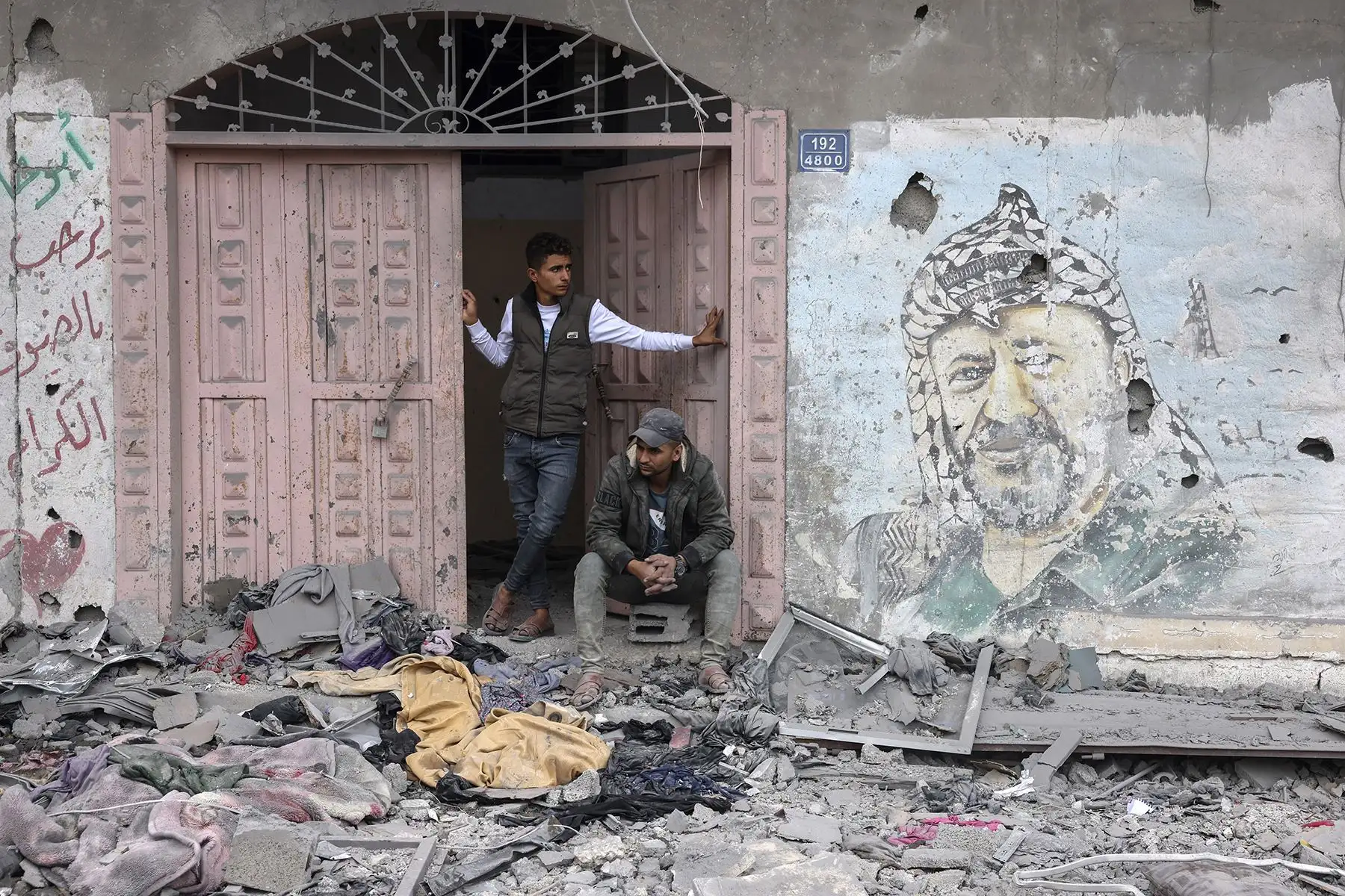 Dos hombres junto a un mural del líder palestino Yasser Arafat en medio de los escombros tras el bombardeo israelí en Rafah, en el sur de la Franja de Gaza, el 22 de noviembre de 2023. Foto: AFP