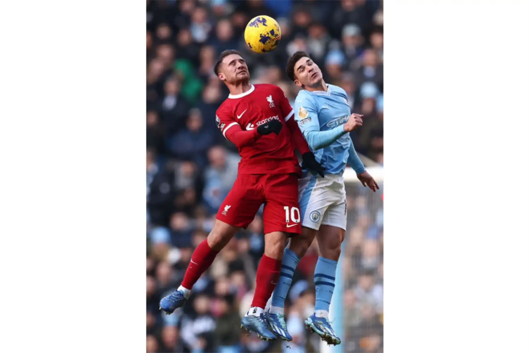 El centrocampista argentino del Liverpool 10 Alexis Mac Allister  y el delantero argentino del Manchester City Julian Alvarez saltan para cabecear el balón durante el partido de fútbol de la Premier League inglesa entre Manchester City y Liverpool en el estadio Etihad de Manchester, noroeste de Inglaterra. Foto: ANDINA/AFP