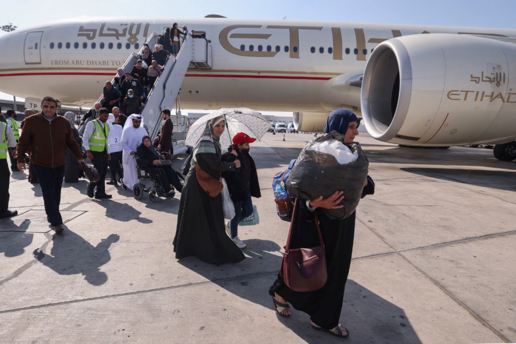 Los palestinos evacuados de la Franja de Gaza que llegaron en un avión desde el aeropuerto egipcio de El-Arish desembarcan al aterrizar en Abu Dhabi. Foto: AFP