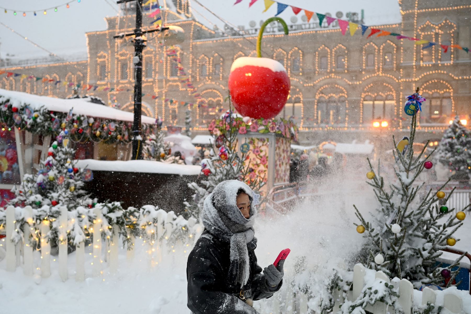 Una mujer pasa junto a los puestos del mercado navideño en la Plaza Roja cubierta de nieve en Moscú.
 Foto: AFP