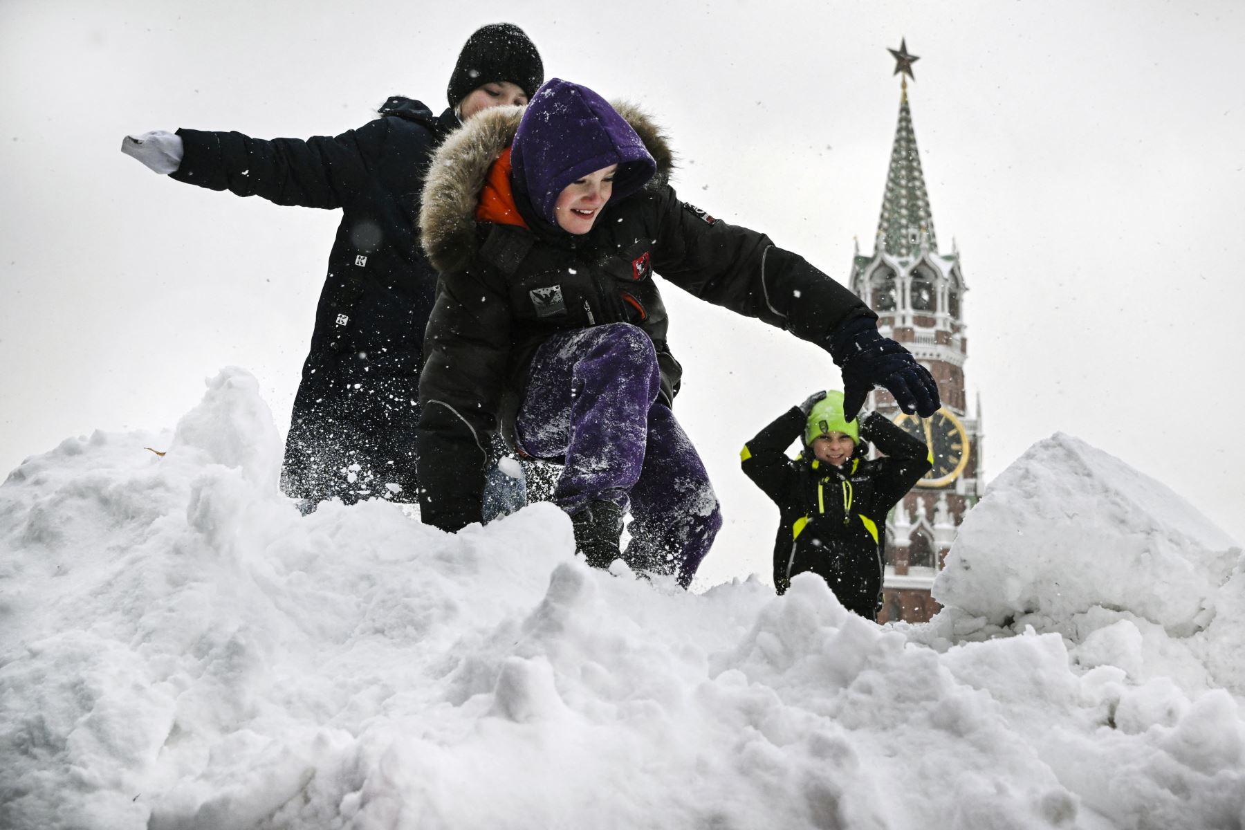 Los niños juegan en la cima de una colina nevada en la Plaza Roja frente a la torre Spasskaya del Kremlin después de una fuerte nevada en Moscú. Foto: AFP