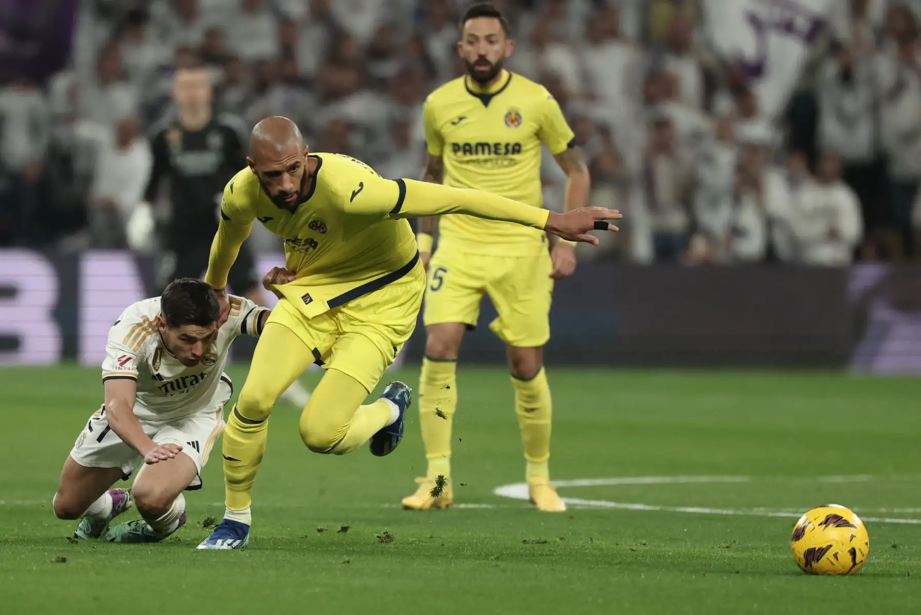 El delantero español del Real Madrid, Brahim Díaz cae sobre el terreno de juego mientras lucha por el balón con el centrocampista francés del Villarreal, Etienne Capoue durante el partido de fútbol de la liga española entre el Real Madrid CF y el Villarreal CF en el estadio Santiago Bernabeu de Madrid. 
Foto: AFP