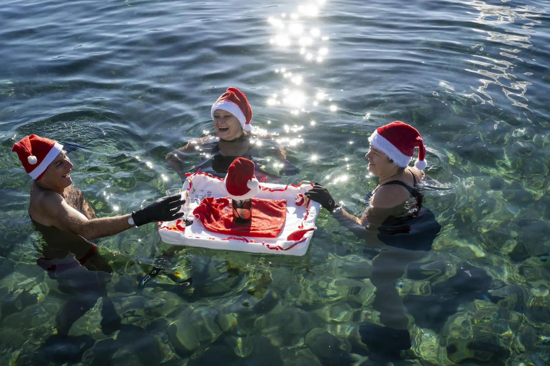 Personas vestidas con gorros de Papá Noel nadan en aguas a 8 grados en el lago Leman en Bains des Paquis en la víspera de la navidad en Ginebra, Suiza. Foto: EFE