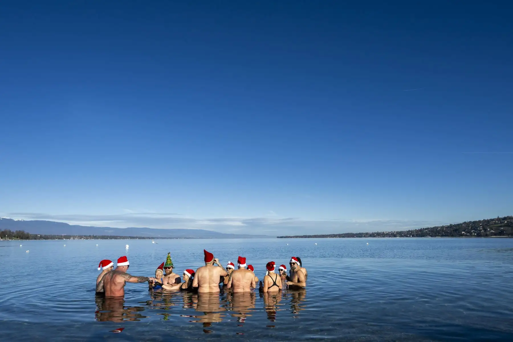 Personas vestidas con gorros de Papá Noel nadan en aguas a 8 grados en el lago Leman en Bains des Paquis en la víspera de la navidad en Ginebra, Suiza. Foto: EFE