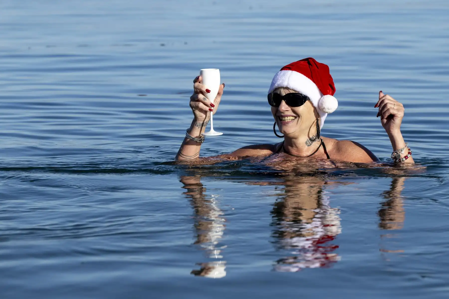 Personas vestidas con gorros de Papá Noel nadan en aguas a 8 grados en el lago Leman en Bains des Paquis en la víspera de la navidad en Ginebra, Suiza. Foto: EFE