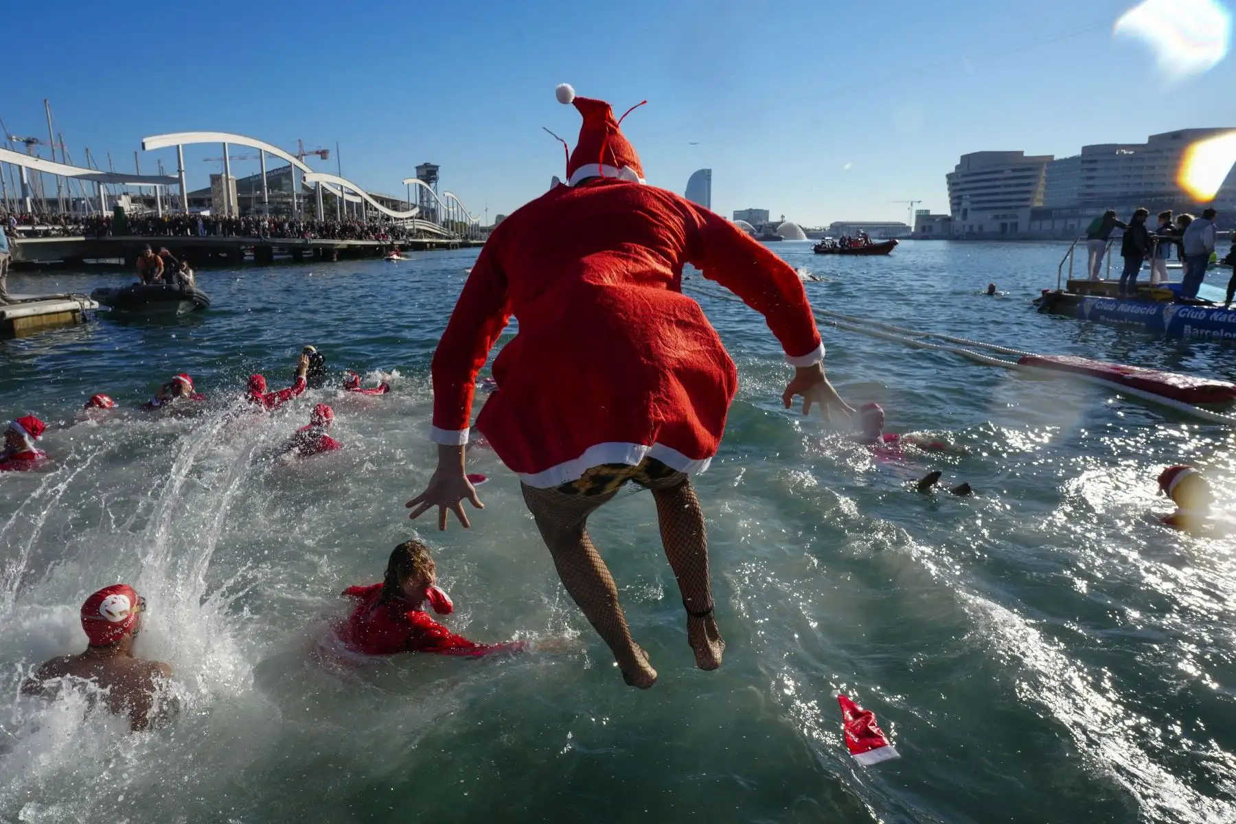 Varios participantes se lanzan este lunes al agua durante la celebración de la 114 edición de la Copa Nadal, que como es tradicional se celebra el día de Navidad en el Puerto de Barcelona, y que batirá este año el récord histórico de participación con un total de 424 inscritos. 
Foto: EFE