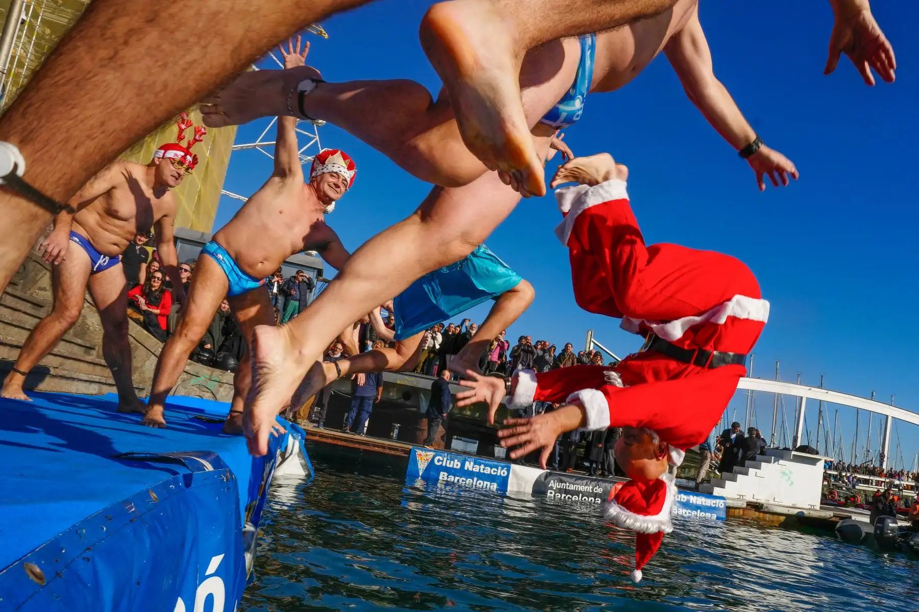 Varios participantes se lanzan este lunes al agua durante la celebración de la 114 edición de la Copa Nadal, que como es tradicional se celebra el día de Navidad en el Puerto de Barcelona, y que batirá este año el récord histórico de participación con un total de 424 inscritos.
Foto: EFE