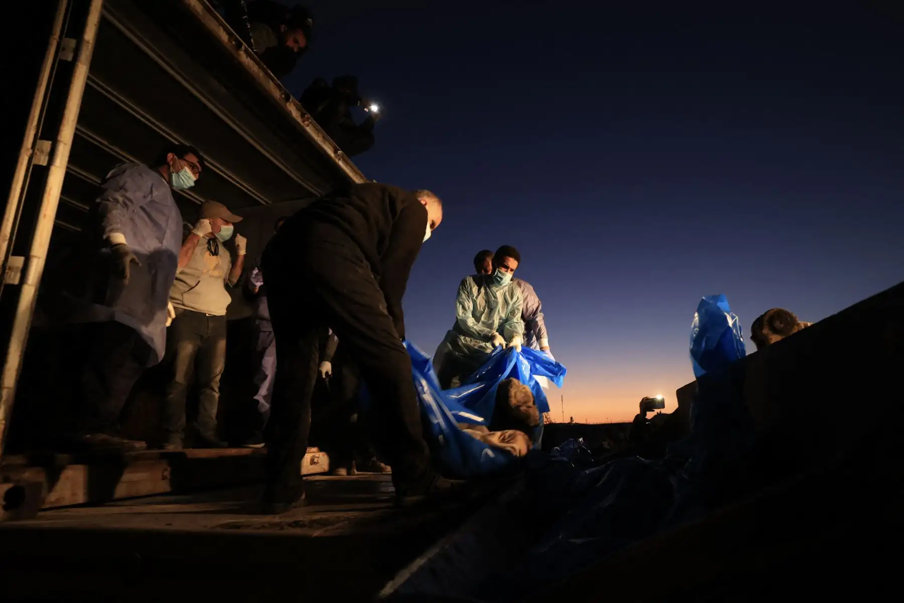 Los cuerpos amortajados de los palestinos asesinados en el norte de Gaza, que fueron capturados y posteriormente liberados por Israel, se descargan de un contenedor para ser enterrados en una fosa común en Rafah, en el sur de la Franja de Gaza, el 26 de diciembre de 2023, en medio de las batallas en curso entre Israel. y el grupo militante Hamás.

Foto: AFP