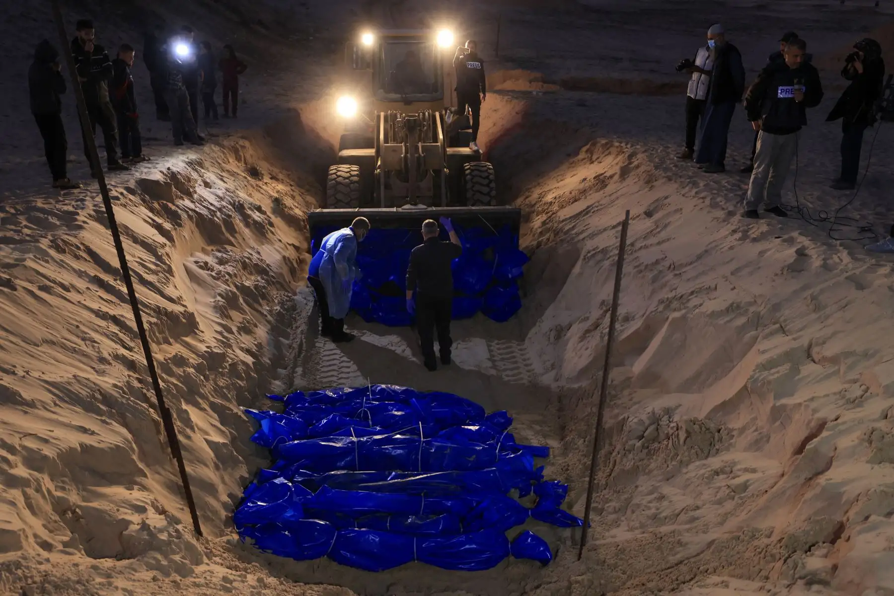 Los cuerpos amortajados de los palestinos asesinados en el norte de Gaza, que fueron capturados y posteriormente liberados por Israel, son enterrados en una fosa común en Rafah, en el sur de la Franja de Gaza, el 26 de diciembre de 2023, en medio de las batallas en curso entre Israel y el grupo militante Hamás.

Foto: AFP