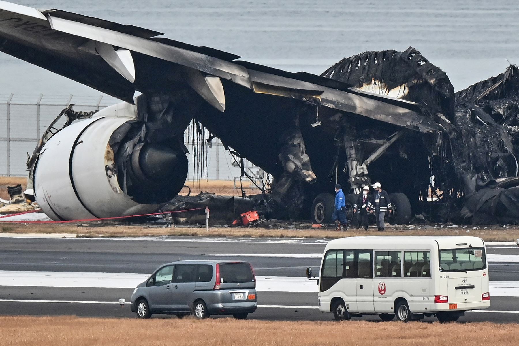 Los funcionarios observan los restos quemados de un avión de pasajeros de Japan Airlines (JAL) en la pista del Aeropuerto Internacional de Tokio en Haneda en Tokio.
Foto: AFP