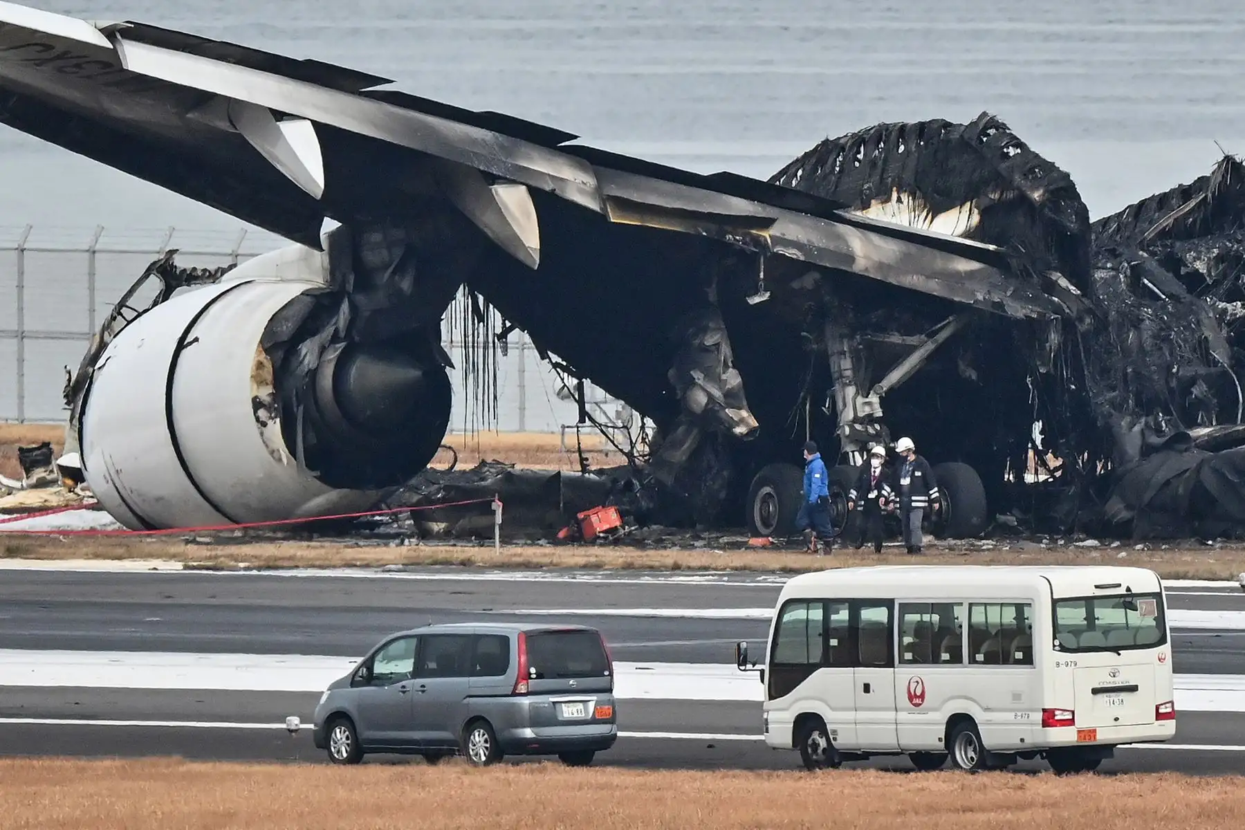 Los funcionarios observan los restos quemados de un avión de pasajeros de Japan Airlines (JAL) en la pista del Aeropuerto Internacional de Tokio en Haneda en Tokio.
Foto: AFP