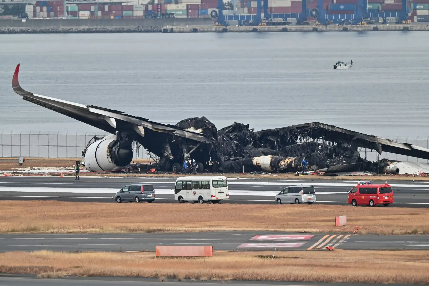 Los funcionarios observan los restos quemados de un avión de pasajeros de Japan Airlines (JAL) en la pista del Aeropuerto Internacional de Tokio en Haneda en Tokio.
Foto: AFP