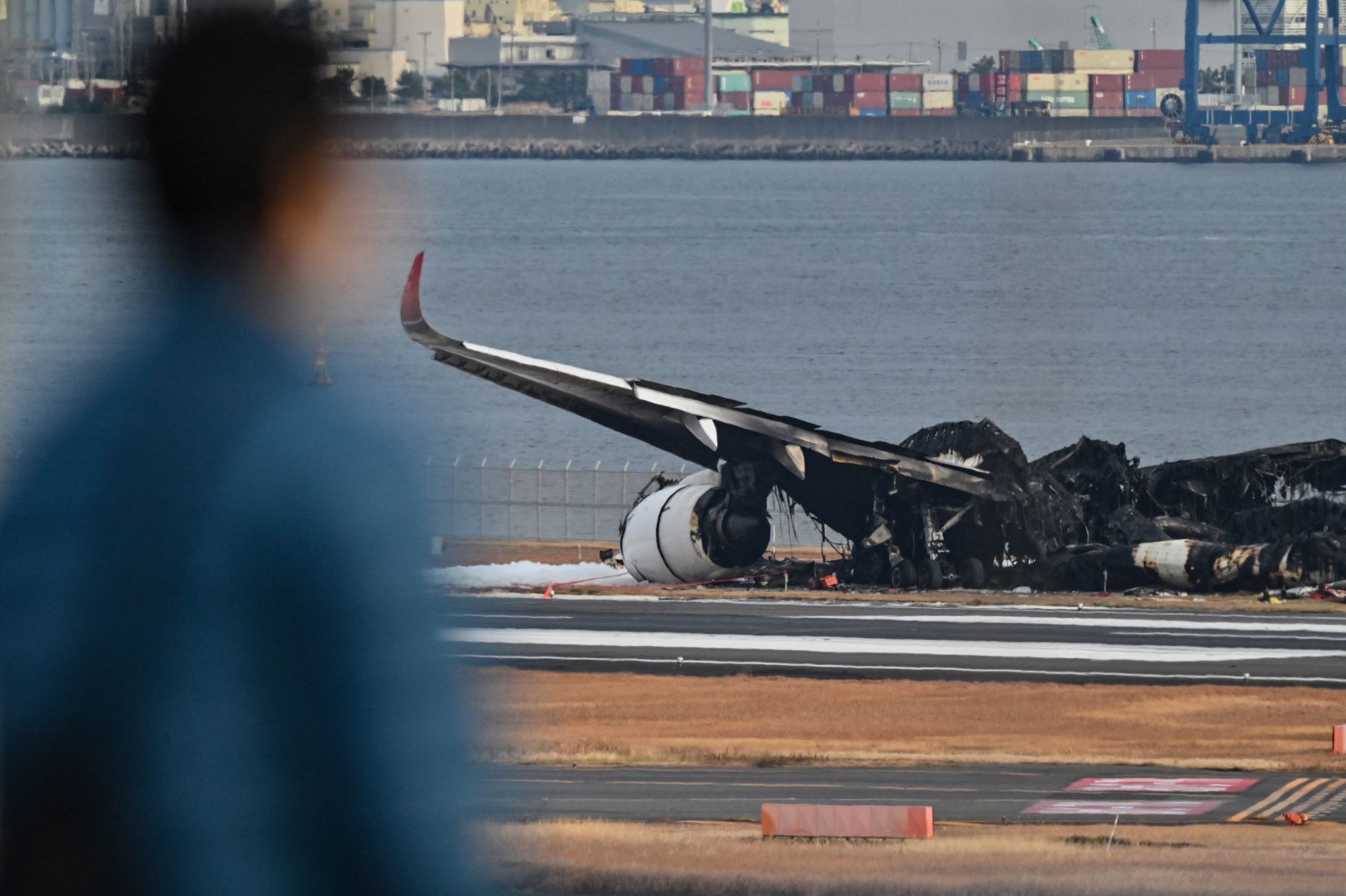 Un hombre observa los restos quemados de un avión de pasajeros de Japan Airlines (JAL) en la pista del Aeropuerto Internacional de Tokio en Haneda en Tokio.Foto: AFP/Archivo