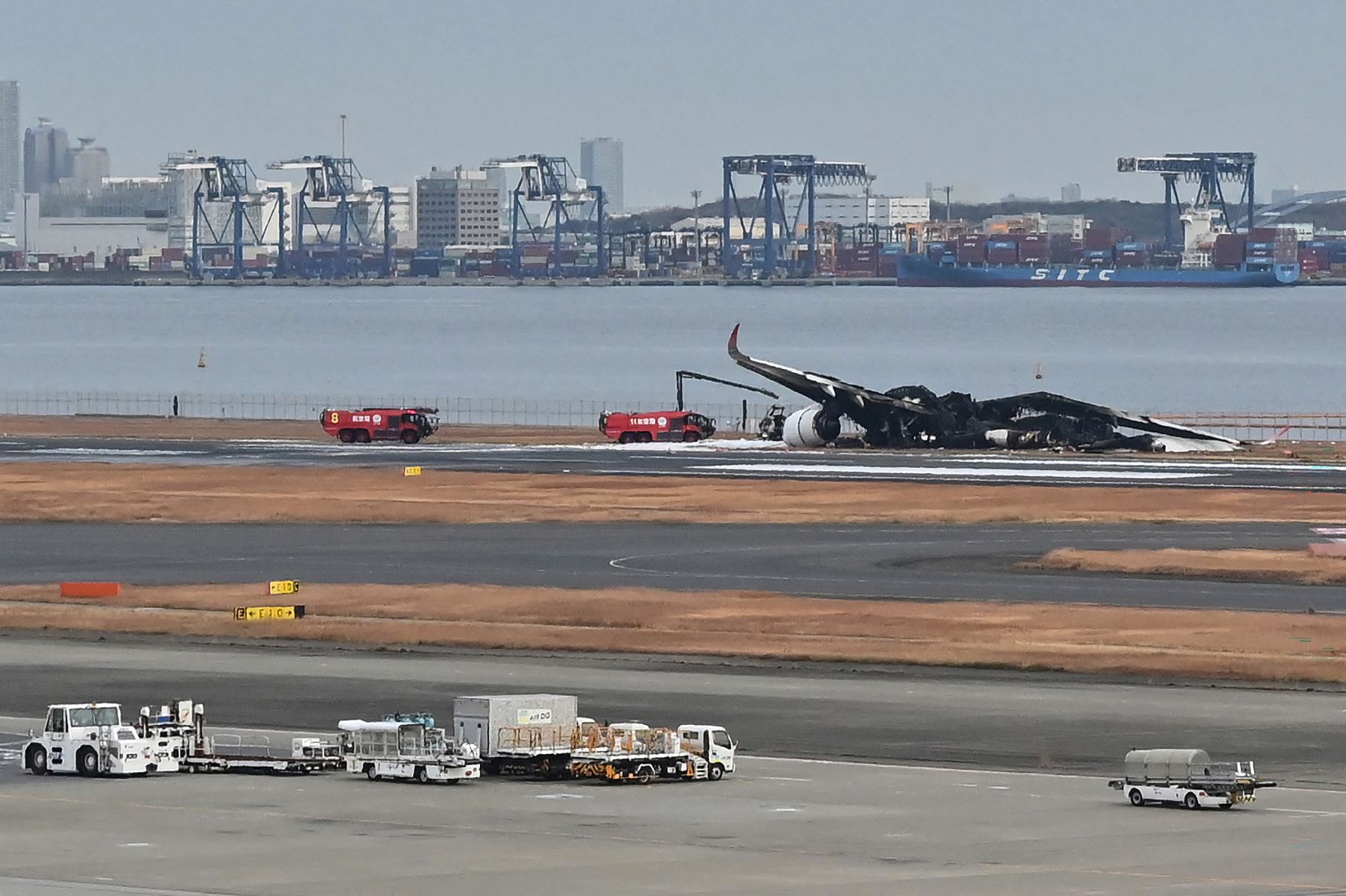 Los camiones de bomberos están estacionados junto a los restos quemados de un avión de pasajeros de Japan Airlines (JAL) en la pista del Aeropuerto Internacional de Tokio en Haneda en Tokio.
Foto: AFP