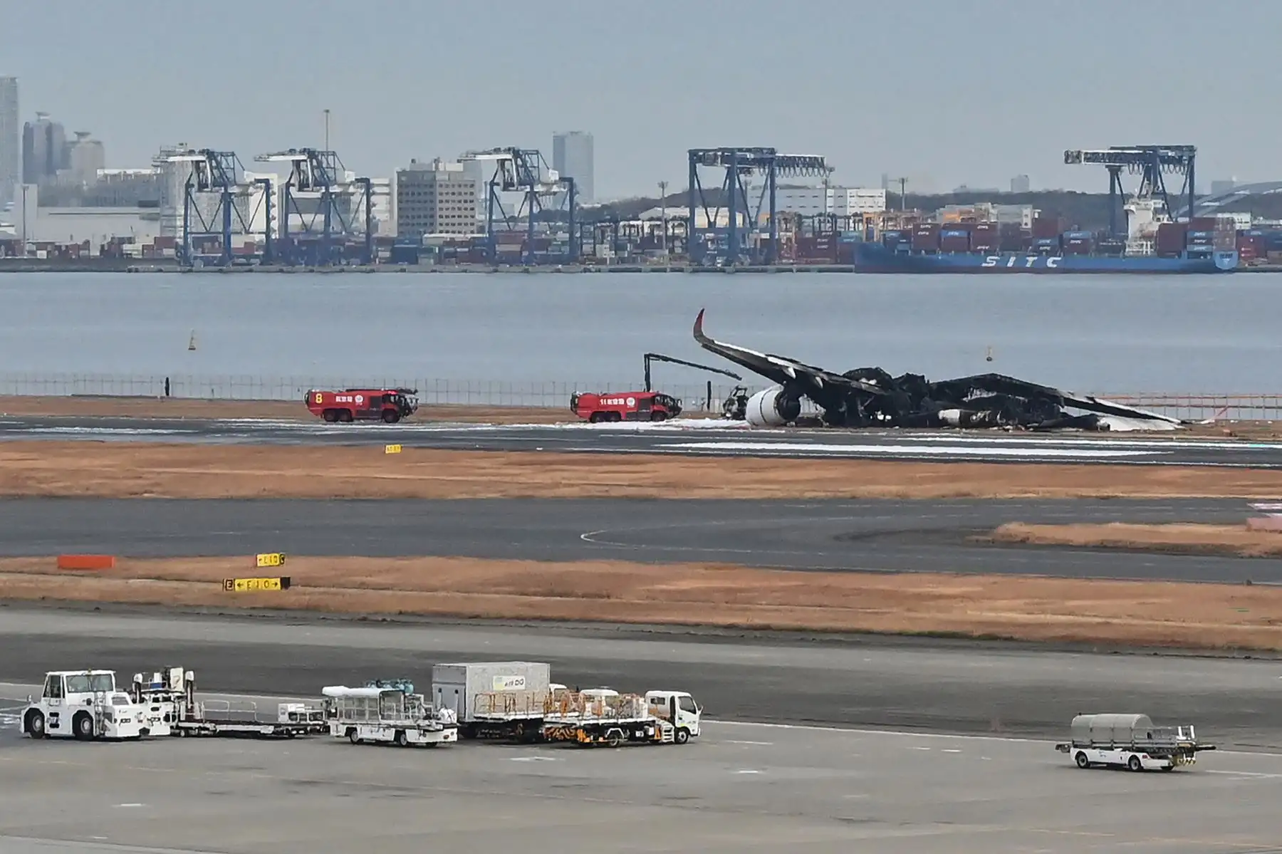 Los camiones de bomberos están estacionados junto a los restos quemados de un avión de pasajeros de Japan Airlines (JAL) en la pista del Aeropuerto Internacional de Tokio en Haneda en Tokio.
Foto: AFP