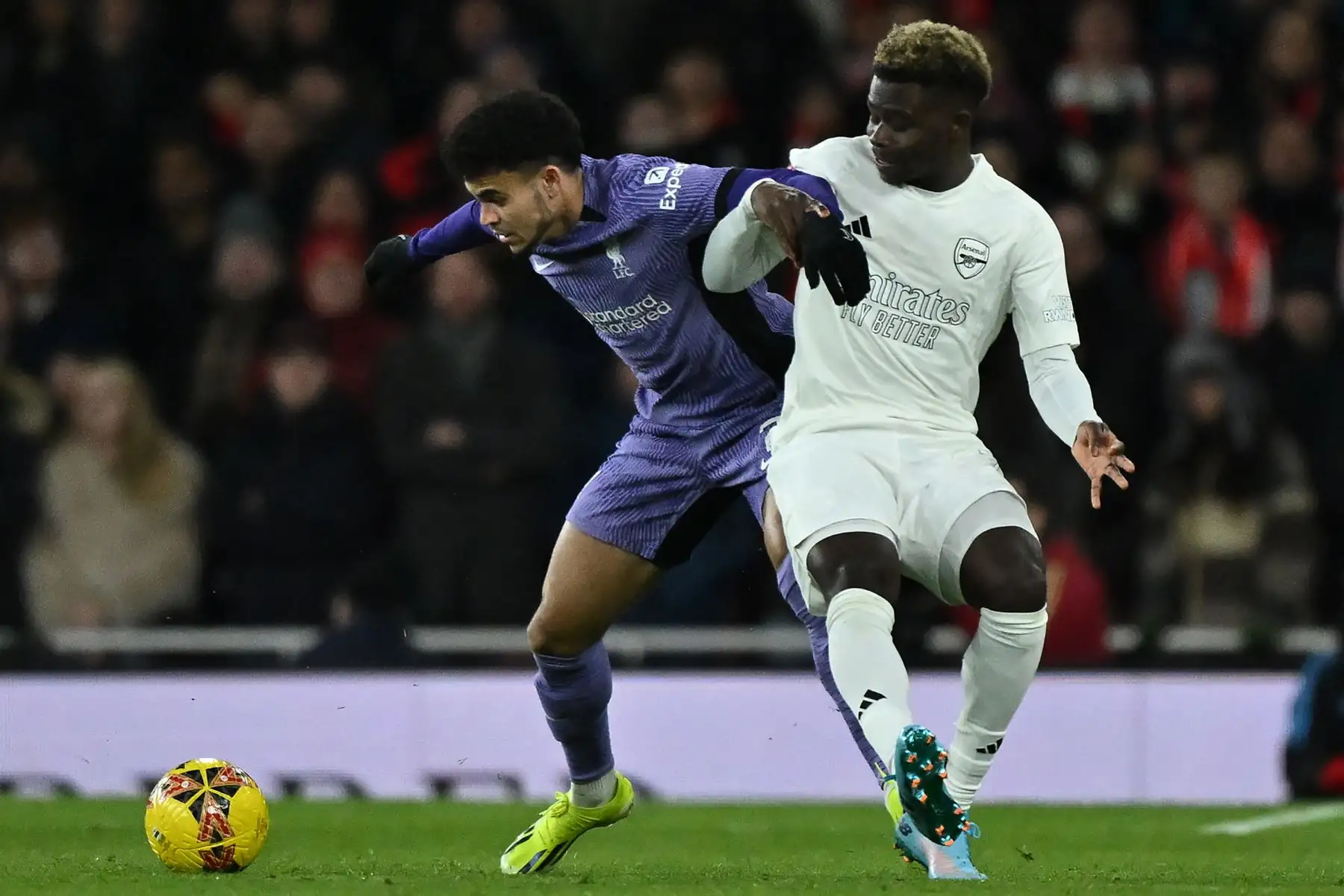 El centrocampista colombiano del Liverpool  Luis Díaz  compite con el centrocampista inglés del Arsenal Bukayo Saka durante el partido de fútbol de tercera ronda de la Copa FA inglesa entre Arsenal y Liverpool en el Emirates Stadium de Londres. Foto: ANDINA/AFP