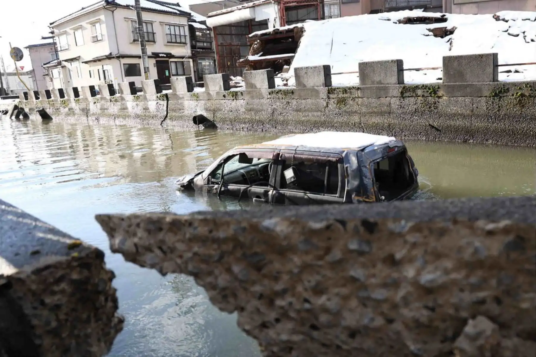 Un vehículo que  fue arrastrado por el tsunami se encuentra en el agua junto a edificios dañados en la ciudad de Noto, prefectura de Ishikawa, afectada por el desastre, el 9 de enero de 2024, después de que un gran terremoto de magnitud 7,5 sacudiera la región de Noto en la prefectura de Ishikawa el día de Año Nuevo. Foto: AFP