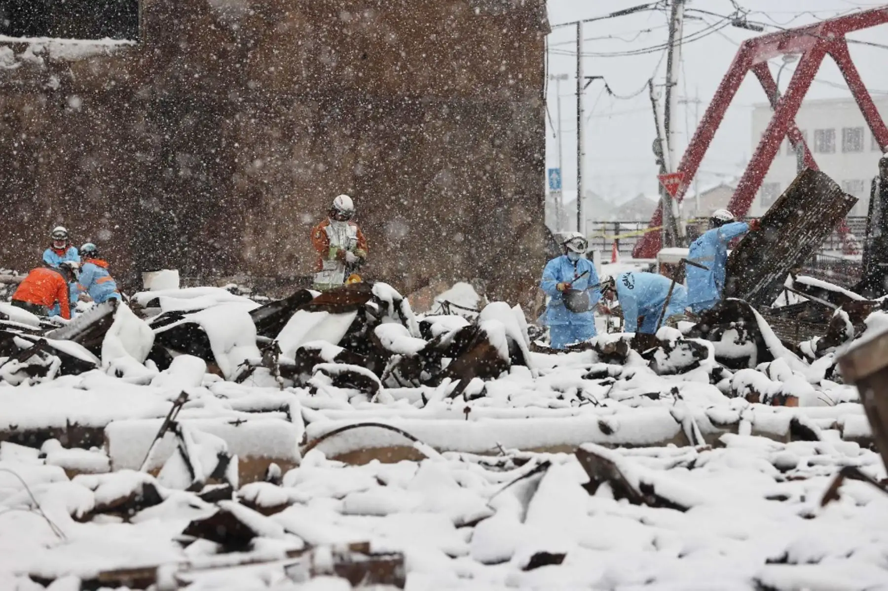 Los bomberos buscan personas desaparecidas en las ruinas quemadas del mercado de Wajima mientras la nieve cubre parte del área afectada por el desastre en la ciudad de Wajima, prefectura de Ishikawa, el 8 de enero de 2024, una semana después de que un gran terremoto de magnitud 7,5 sacudiera la región de Noto en Ishikawa. Foto: AFP