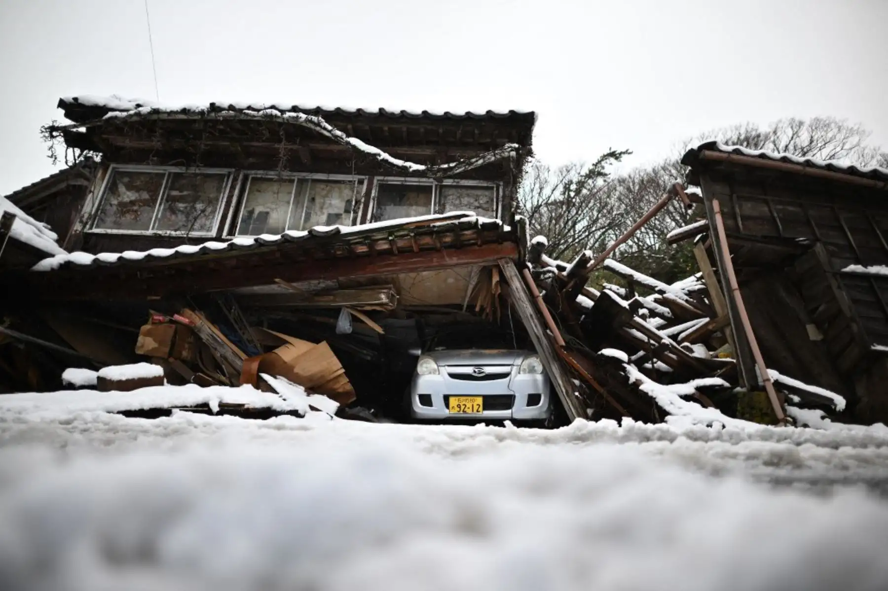 Un automóvil dañado yace debajo de un edificio derrumbado en la ciudad de Shika en el distrito de Hakui, prefectura de Ishikawa, el 8 de enero de 2024, después de que un gran terremoto de magnitud 7,5 sacudiera la región de Noto el día de Año Nuevo. Foto: AFP