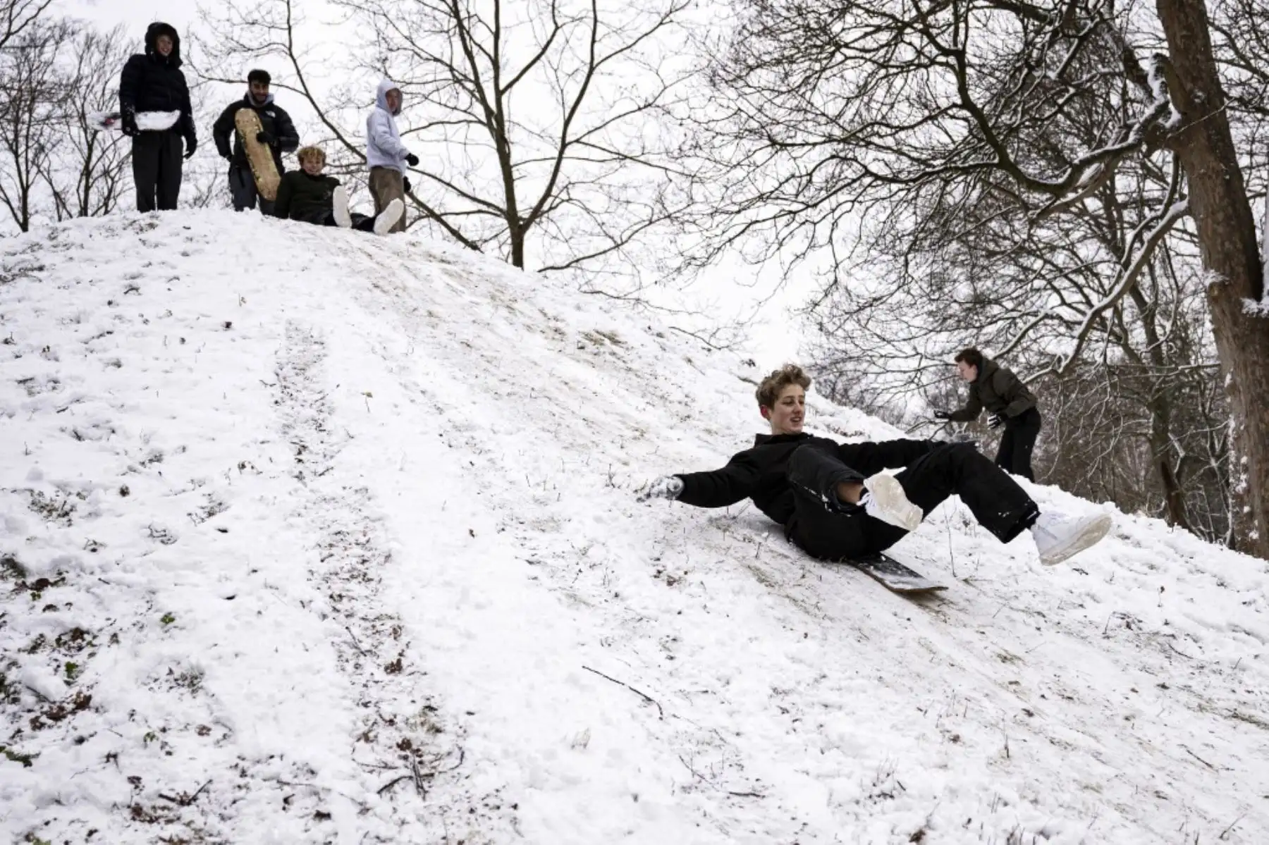 Un grupo de niños bajan en trineo por una colina cubierta de nieve en el parque Soendermarken, Frederiksberg en Copenhague, Dinamarca, el 17 de enero de 2024. Foto: AFP