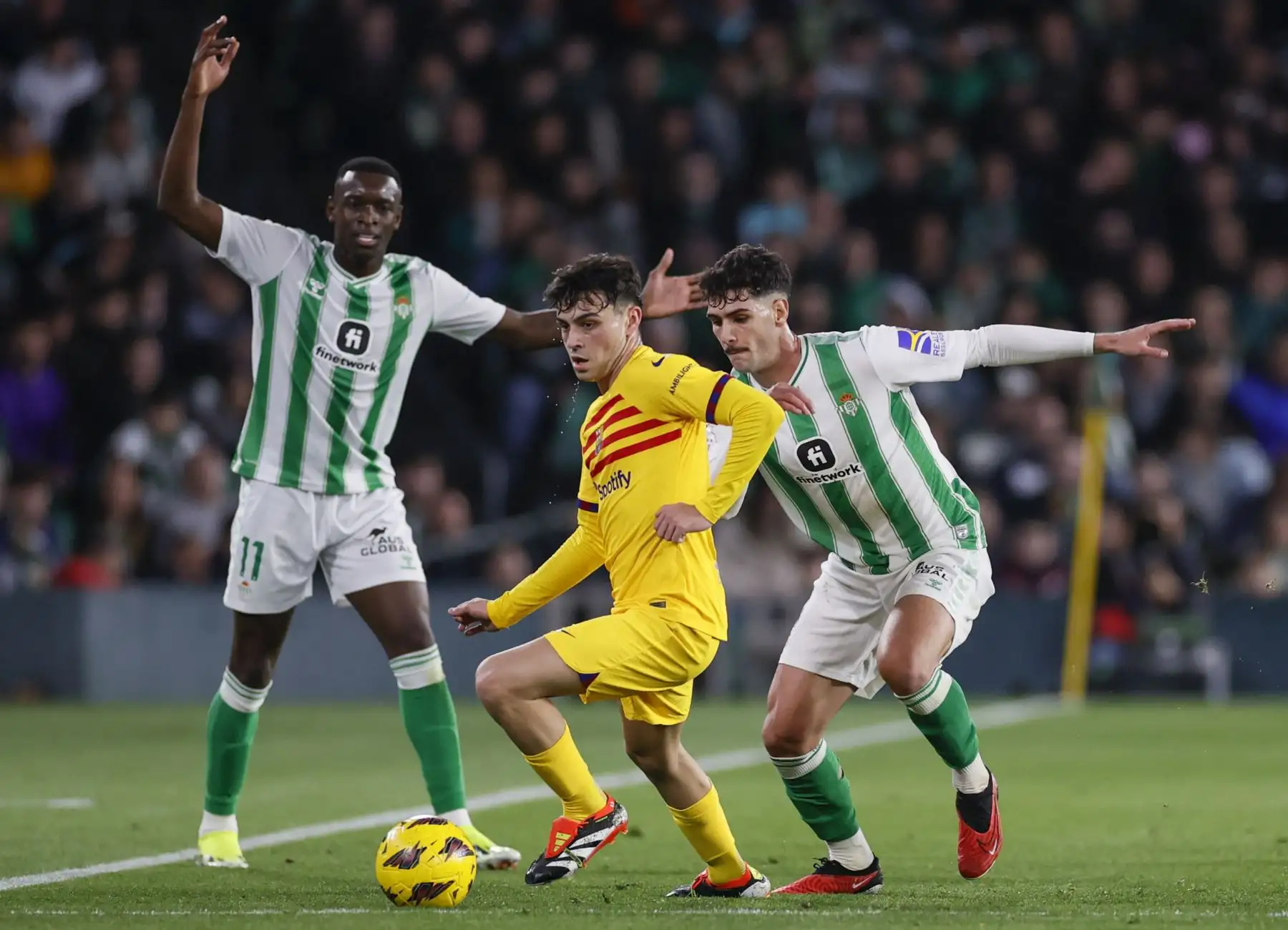 El centrocampista del FC Barcelona, Pedri, se lleva el balón ante los jugadores del Betis, el estadounidense Johnny (d) y el brasileño Luiz Henrique, durante el encuentro correspondiente a la jornada 21 de la Liga EA Sports que Betis y FC Barcelona disputan este domingo en el estadio Benito Villamarín de Sevilla. Foto: ANDINA/EFE