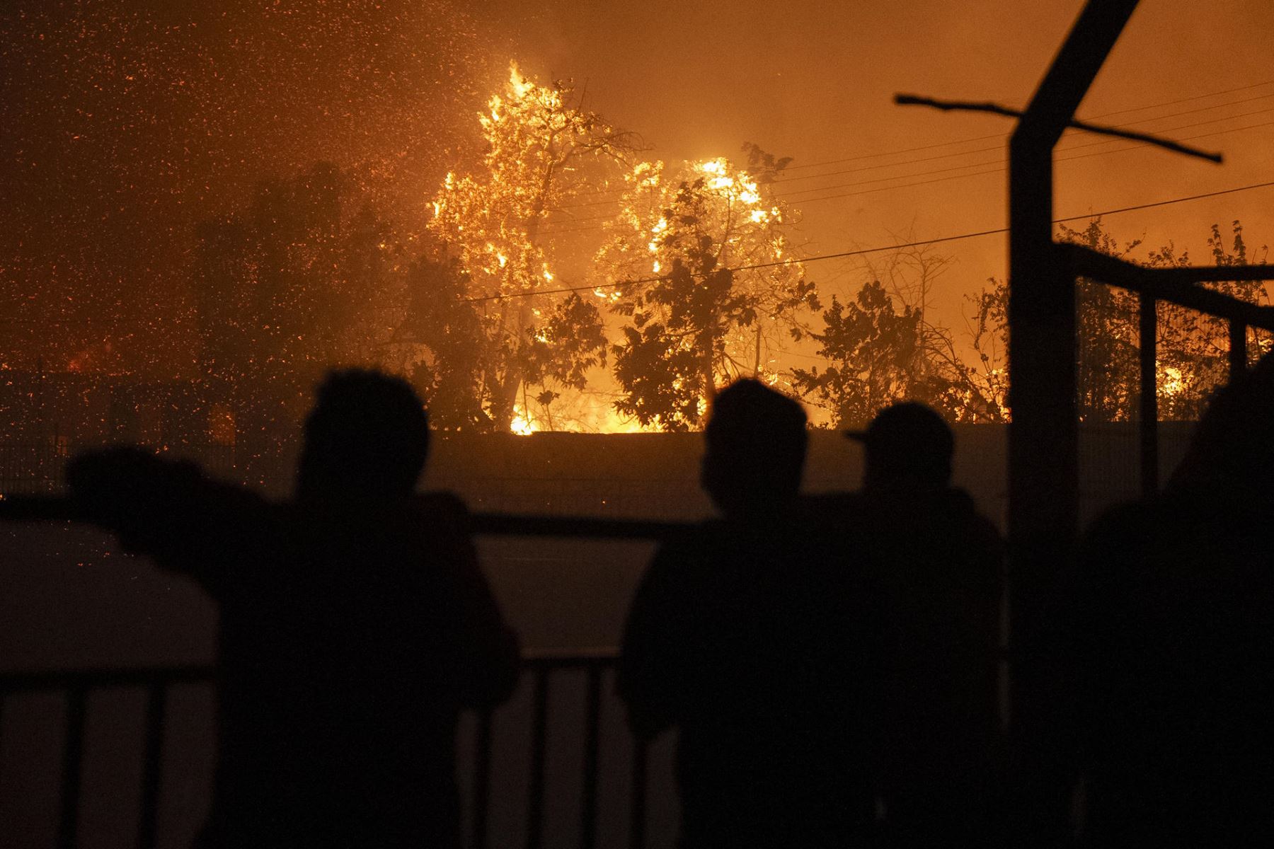 Personas observan un incendio que comenzó en la reserva natural del lago Peñuelas y ha llegado hasta las zonas urbanas hoy, en Viña del Mar (Chile). 
Foto: EFE