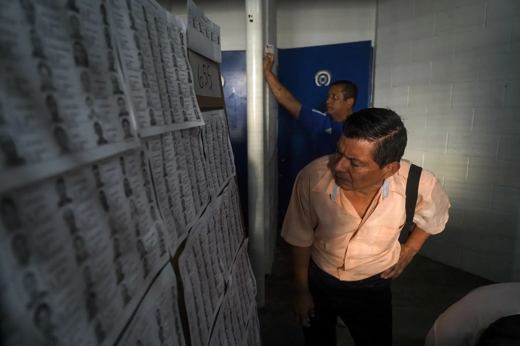 Un hombre revisa las listas de votación durante las elecciones presidenciales y legislativas en un colegio electoral en el barrio Campanera en Soyapango, El Salvador, el 4 de febrero de 2024. El barrio Campanera ha sido un bastión de la pandilla Barrio 18 durante décadas. En diciembre de 2022 se colocó un cerco militar en los alrededores del barrio para combatir frontalmente a las pandillas, aunque vecinos mencionaron que restos de la estructura criminal aún rodean la zona cuando las fuerzas de seguridad se
