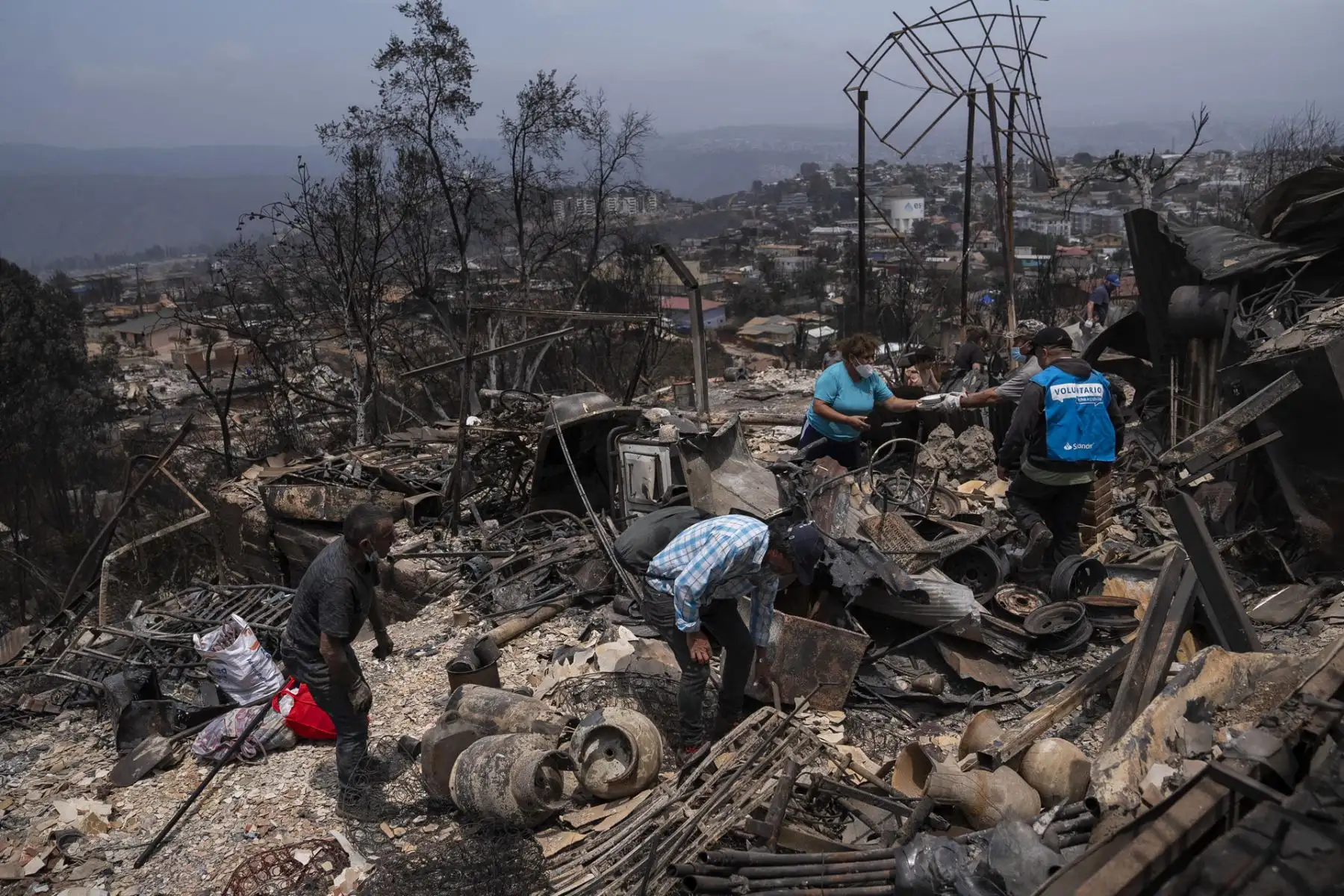 Personas retiran escombros desde una casa en el sector de Achupallas afectada por incendios forestales de Viña del Mar, Región de Valparaiso (Chile). Las autoridades chilenas informaron este domingo de que el número de muertos en los devastadores incendios que han consumido grandes sectores de viviendas en la región de Valparaíso, a 100 kilómetros al este de Santiago sigue en aumento. 
Foto: EFE