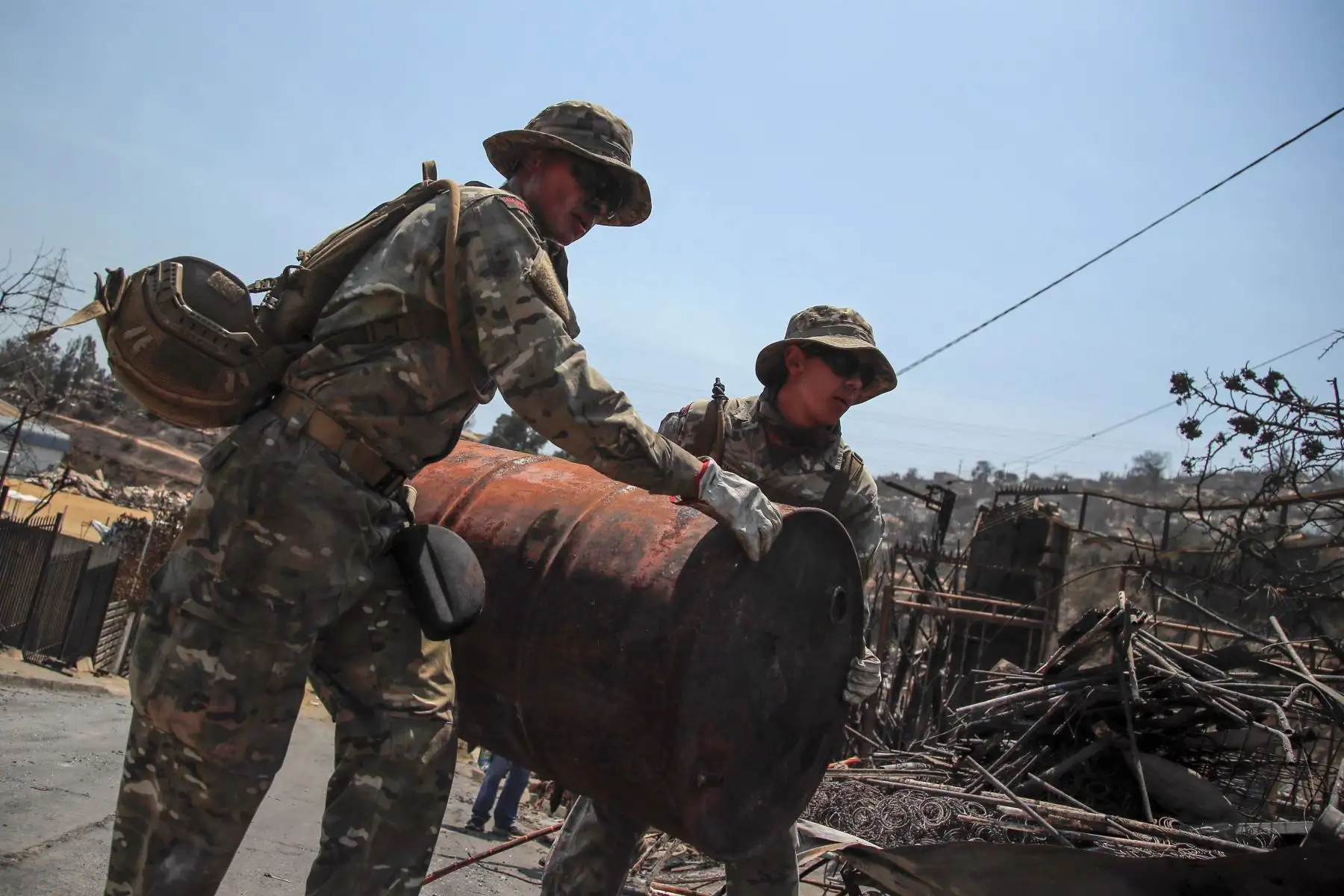 Miembros de la Armada de Chile ayudan en la limpieza de casas quemadas en Villa Independencia, región de Valparaíso. El número de muertos por los incendios forestales en el centro de Chile aumentó a al menos 112 personas el domingo, después de que el presidente Gabriel Boric advirtiera el número aumentaría "significativamente" a medida que los equipos busquen en los barrios destruidos. Foto: ANDINA/AFP