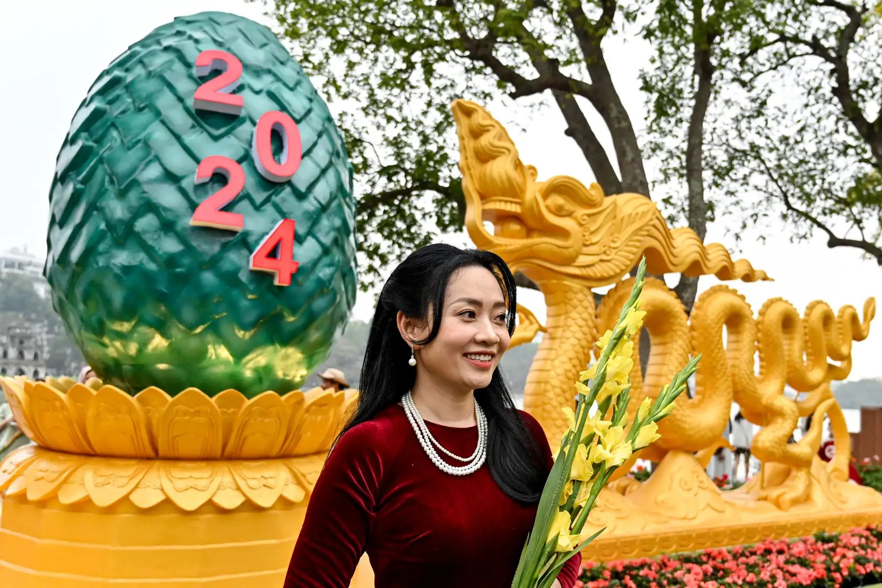 Una mujer posa para una fotografía frente a una instalación con forma de dragón en el lago Hoan Kiem en Hanoi,  mientras los vietnamitas se preparan para celebrar su tradicional Tet o Año Nuevo Lunar del Dragón.
Foto: AFP