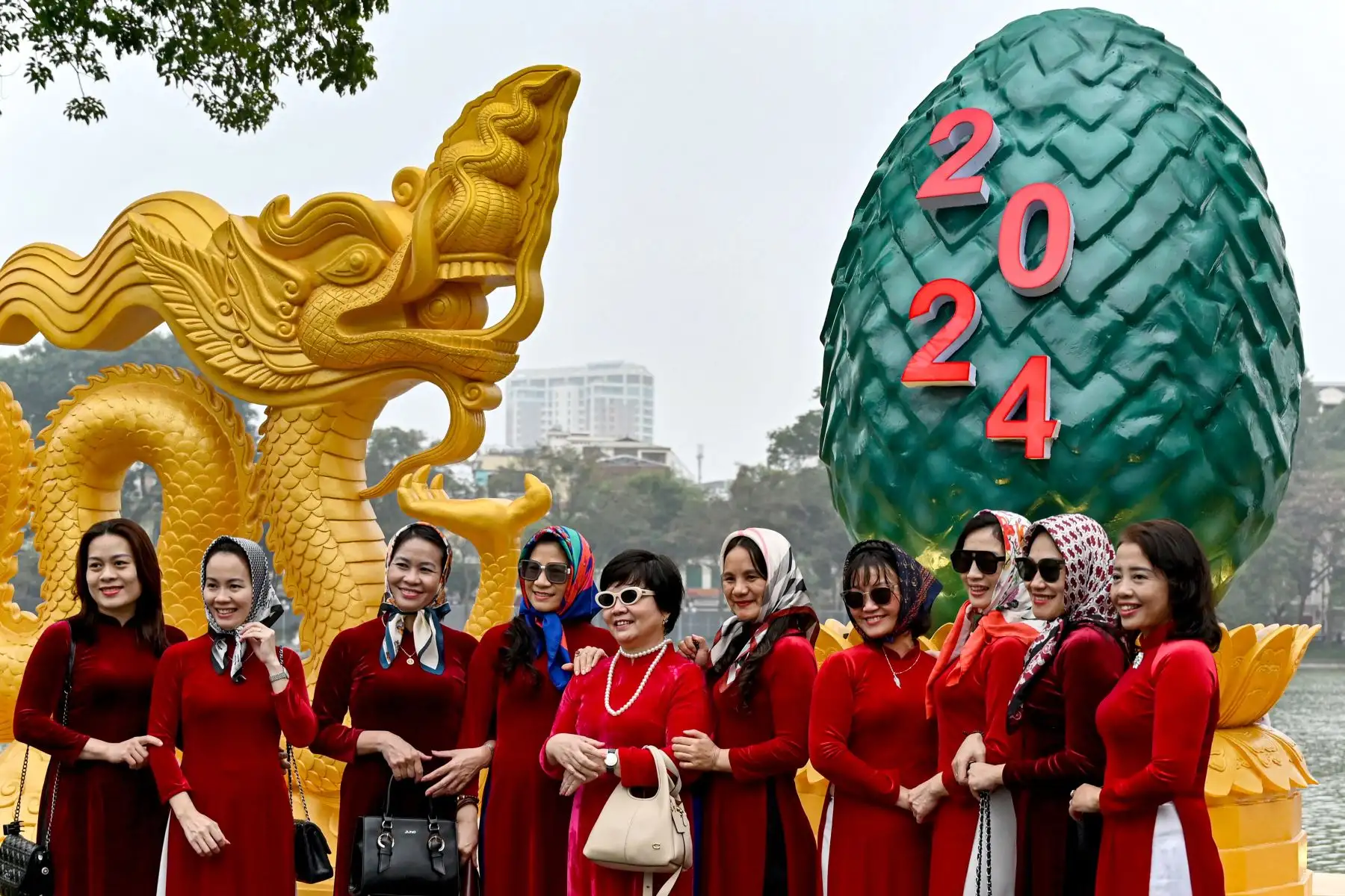 Mujeres posan para una fotografía frente a una instalación con forma de dragón en el lago Hoan Kiem en Hanoi el 6 de febrero de 2024, mientras los vietnamitas se preparan para celebrar su tradicional Tet o Año Nuevo Lunar del Dragón. Foto: ANDINA/AFP