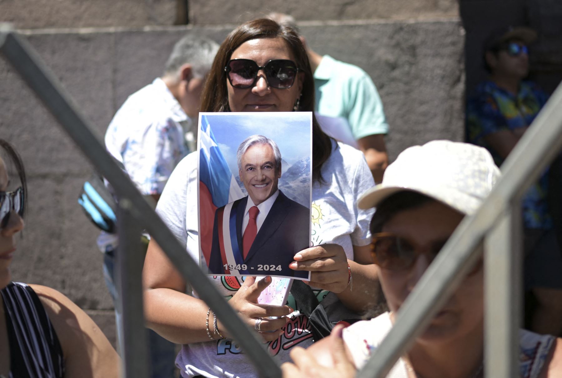 Una partidaria del fallecido ex presidente chileno Sebastián Piñera sostiene una fotografía de él mientras espera ingresar al Palacio del Congreso Nacional en Santiago. Foto: ANDINA/AFP