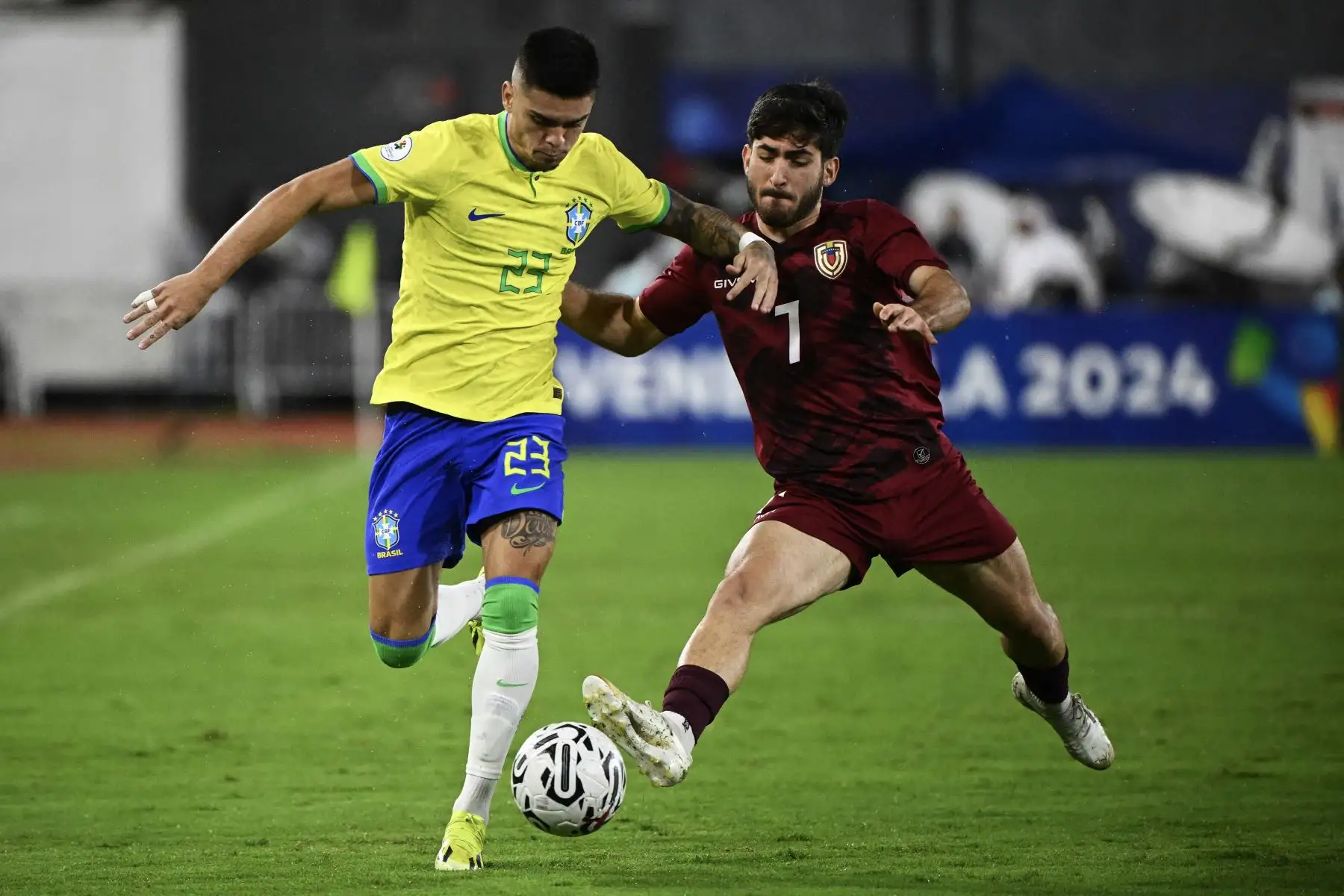 El brasileño Gabriel Pec y el venezolano Matías Lacava  luchan por el balón durante el partido de fútbol del Torneo Preolímpico CONMEBOL Venezuela 2024 entre Venezuela y Brasil en el estadio Brígido Iriarte de Caracas. Foto. ANDINA /AFP
