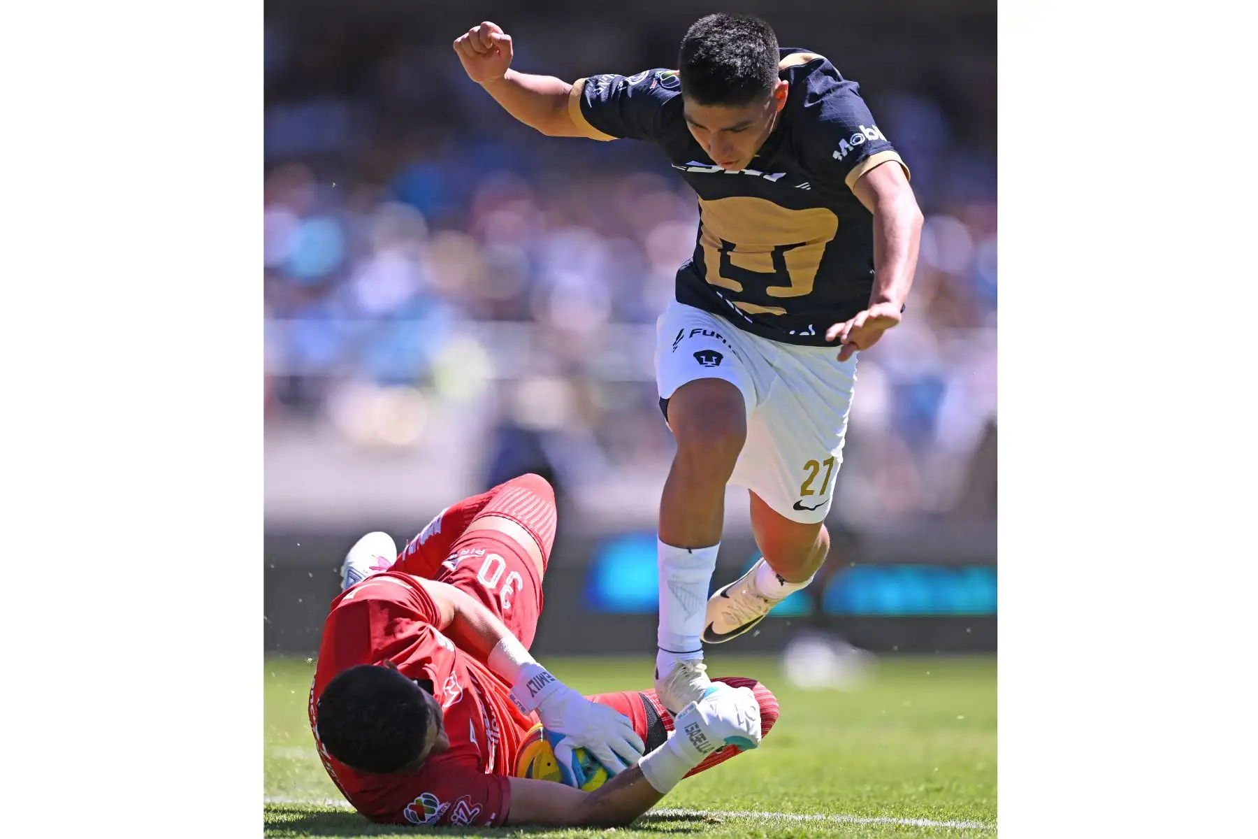 Piero Quispe de Puma y el portero de Puebla Jesús Rodríguez  luchan por el balón durante su partido de fútbol del torneo Clausura mexicano 2024 en el estadio Olímpico Universitario de la Ciudad de México.
Foto: AFP