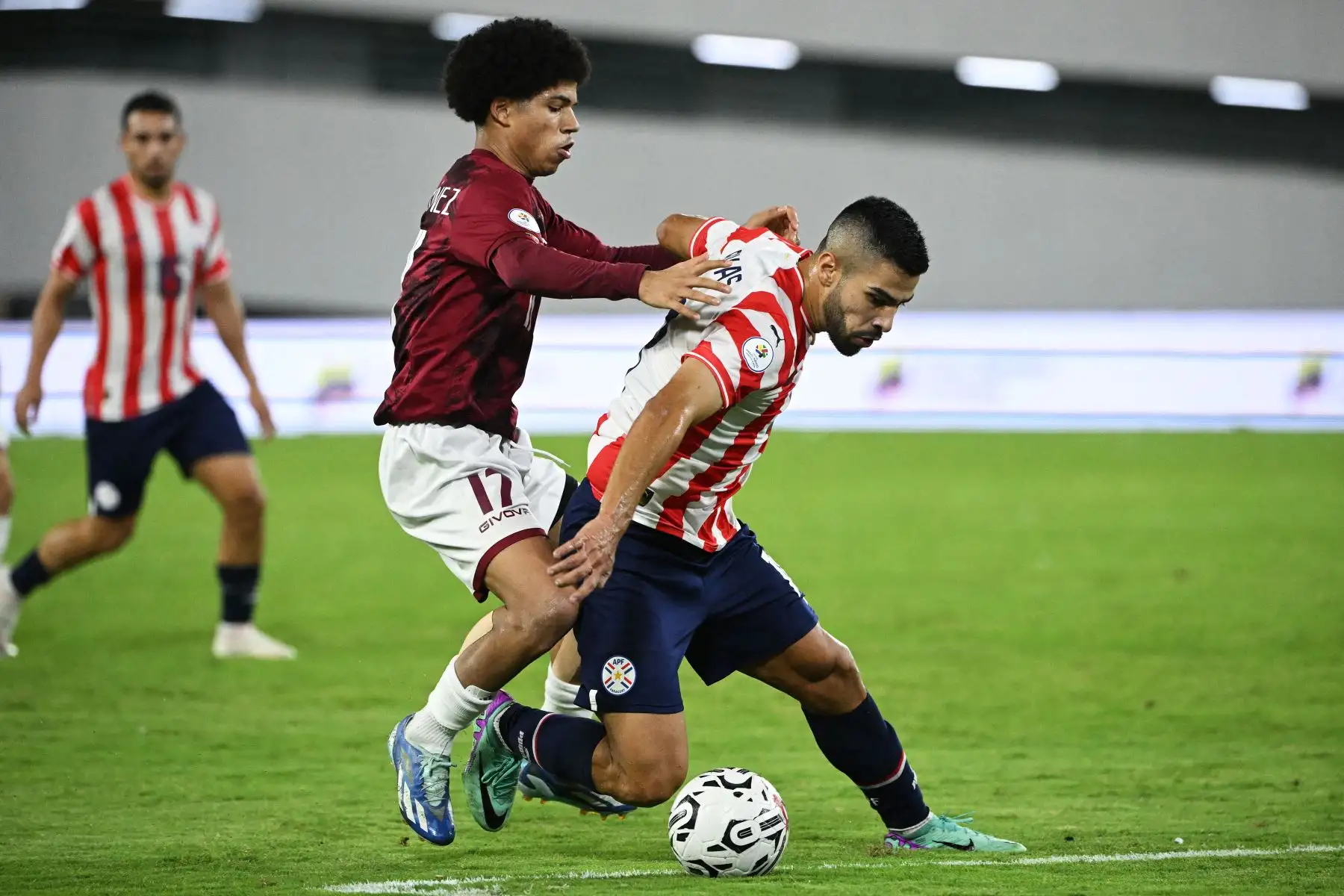 David Martínez de Venezuela y Leonardo Rivas  de Paraguay luchan por el balón durante el partido de fútbol del Torneo Preolímpico CONMEBOL Venezuela 2024 entre Paraguay y Venezuela en el estadio Brígido Iriarte de Caracas.
Foto: AFP
