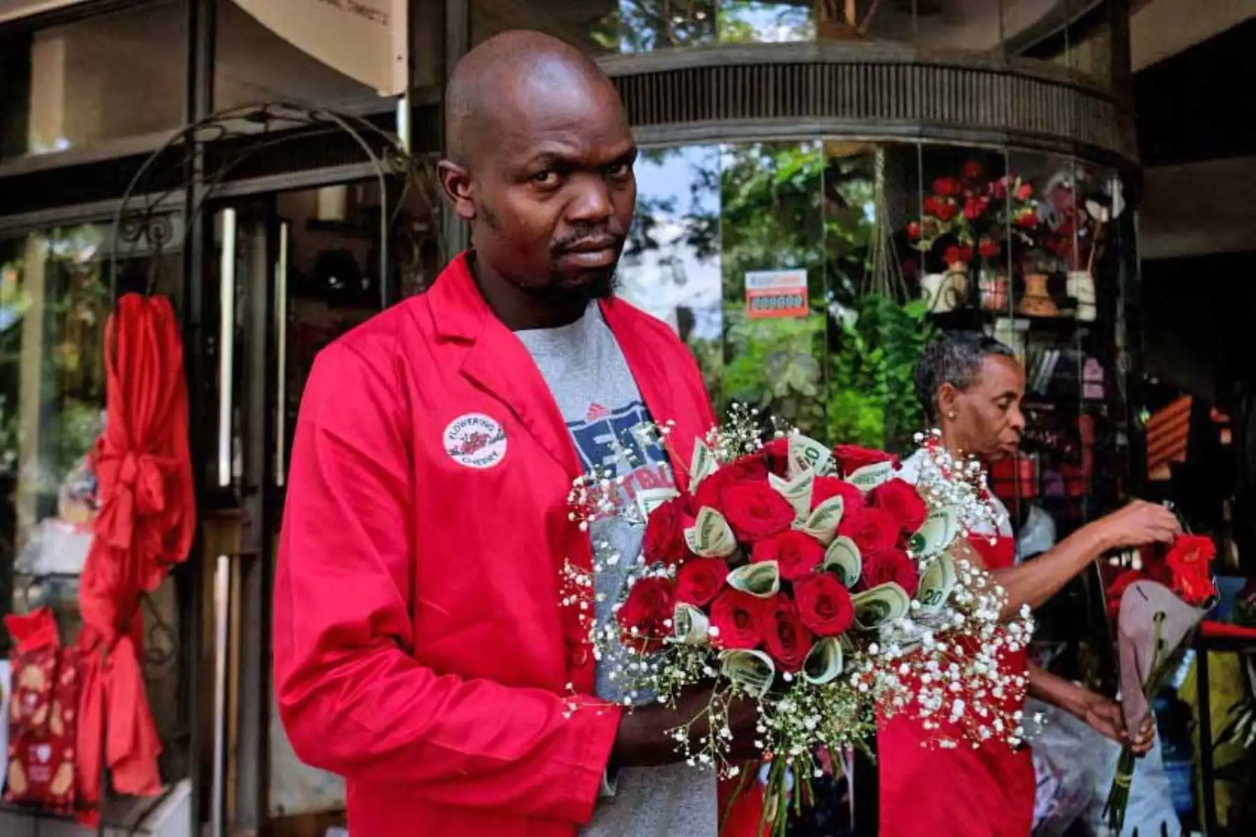Misheck Nyamhotsi posa con su arreglo floral, un "ramo de dinero" del Día de San Valentín que combina tallos de flores cortadas de rosas rojas con hasta quince billetes de 20 dólares en una floristería local en Harare. Foto: AFP