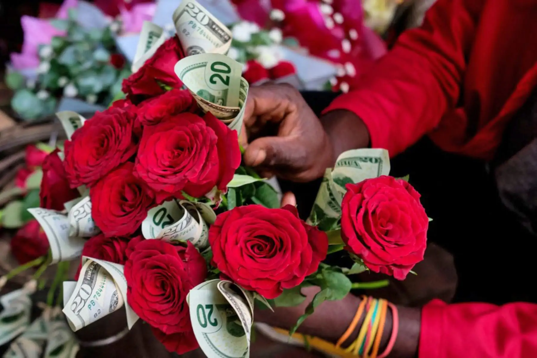 Misheck Nyamhotsi posa con su arreglo floral, un "ramo de dinero" del Día de San Valentín que combina tallos de flores cortadas de rosas rojas con hasta quince billetes de 20 dólares en una floristería local en Harare. Foto: AFP
