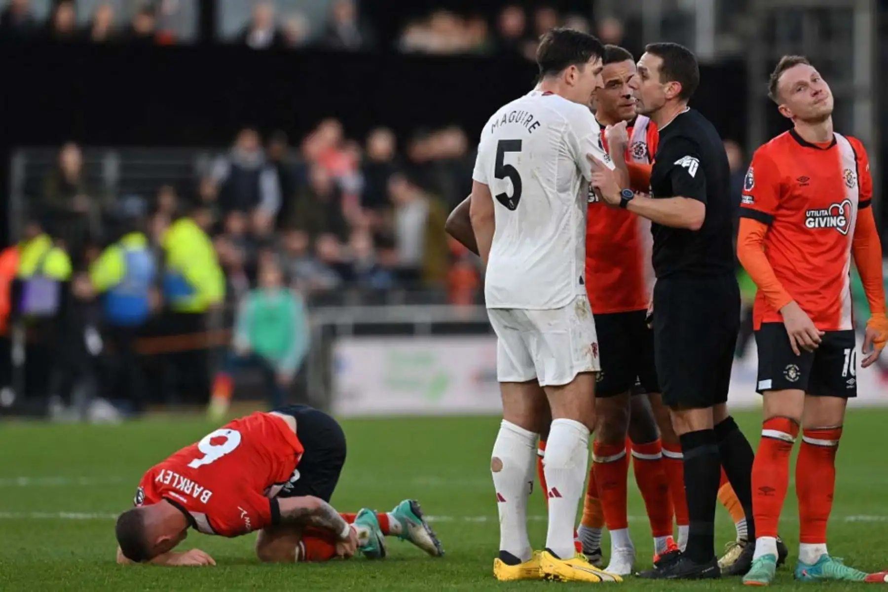 El árbitro inglés David Coote está rodeado de jugadores después de una falta del centrocampista brasileño del Manchester United Casemiro, sobre el mediocampista inglés del Luton Town Ross Barkley. Foto: AFP