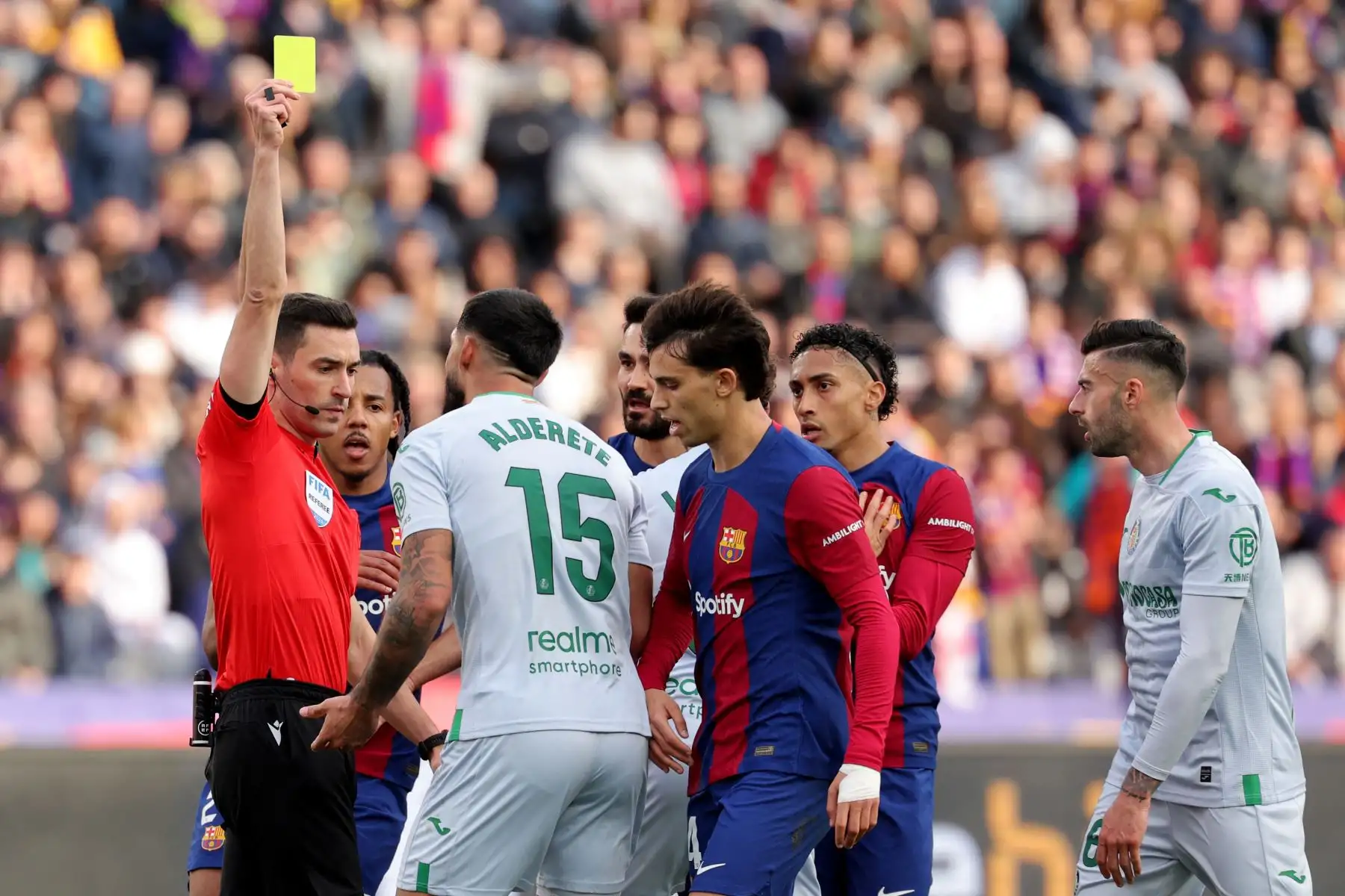 El árbitro español Alejandro Muñiz muestra una tarjeta amarilla al defensa paraguayo del Getafe, Omar Alderete, durante el partido de fútbol de la liga española entre el FC Barcelona y el Getafe CF en el Estadi Olimpic Lluis Companys de Barcelona. Foto: ANDINA/AFP