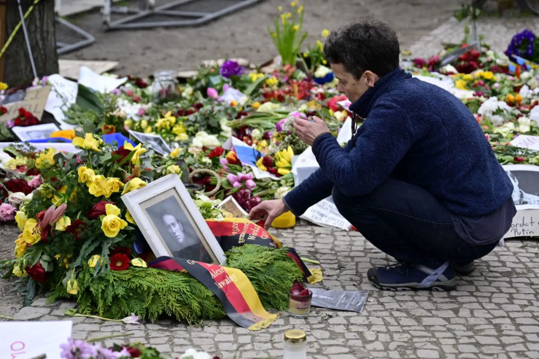 Una mujer enciende una vela en un improvisado monumento con flores y velas para el líder de la oposición rusa Alexei Navalny frente a la embajada rusa en Berlín. Foto: AFP