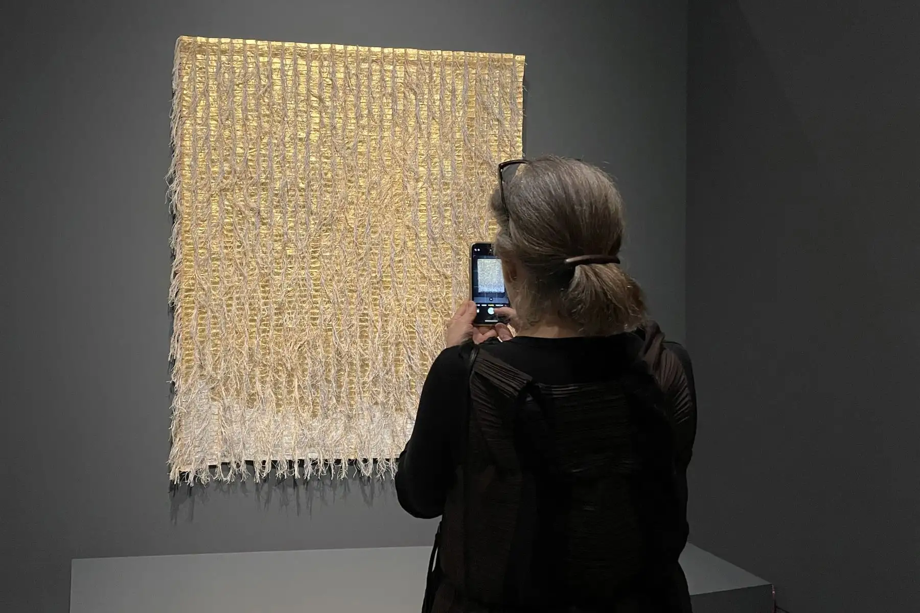 Una mujer toma fotos a una pieza de la exposición 