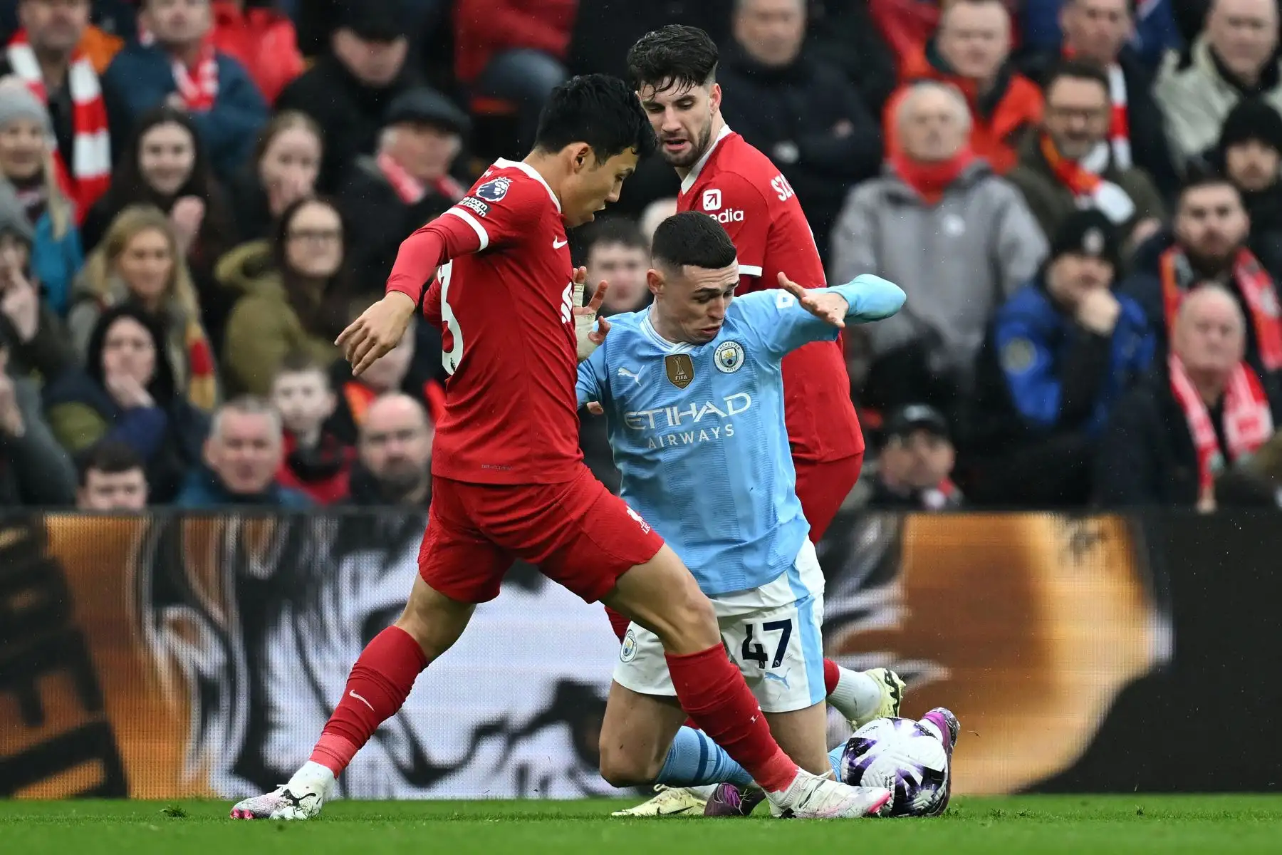 El centrocampista inglés del Manchester City Phil Foden  compite con el centrocampista japonés del Liverpool Wataru Endo y el centrocampista húngaro del Liverpool Dominik Szoboszlai durante el partido de fútbol de la Premier League inglesa entre Liverpool y Manchester City en Anfield en Liverpool. Foto: ANDINA/AFP