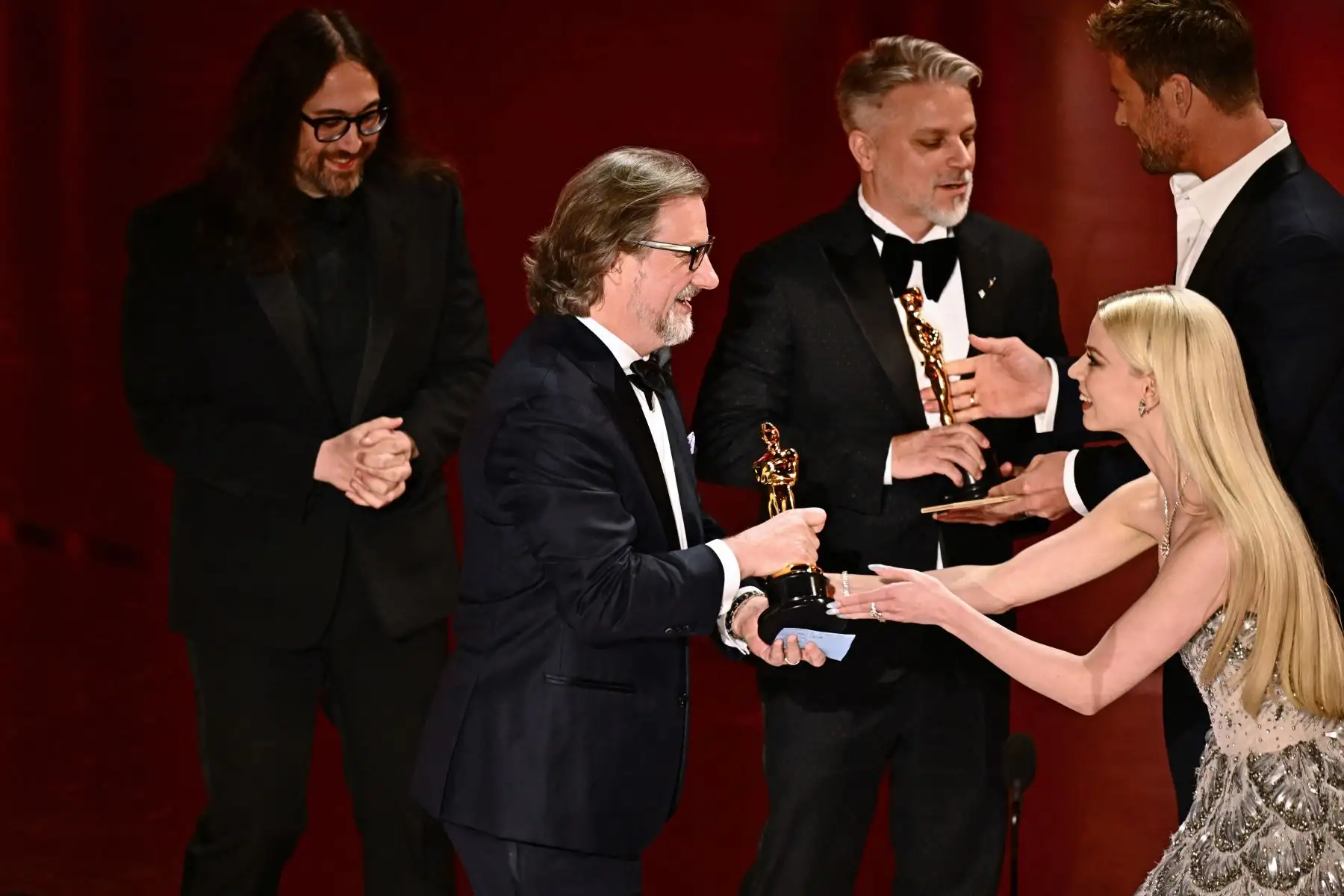 El escritor y director estadounidense Dave Mullins (centro), el productor estadounidense Brad Booker (tercero a la derecha) y el músico estadounidense Sean Ono Lennon (izq) aceptan el premio al Mejor Cortometraje de Animación por "War is Over! Inspired by the Music of John & Yoko" de la actriz estadounidense Anya Taylor-Joy y el actor australiano Chris Hemsworth (R) en el escenario durante la 96ª edición de los Premios Anuales de la Academia en el Dolby Theatre de Hollywood. Foto: AFP