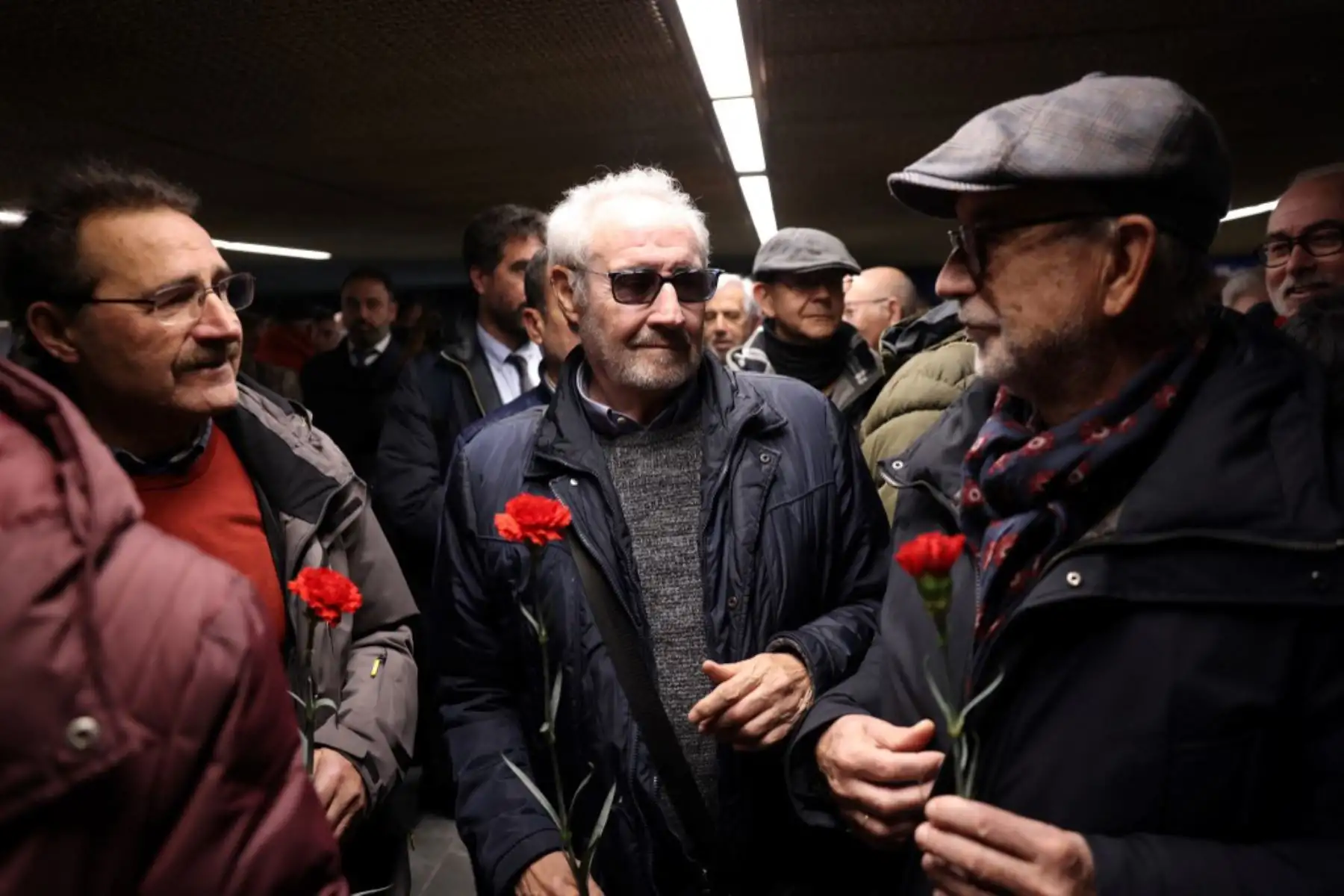 Familiares y amigos de las víctimas de los atentados del 11-M sostienen flores de clavel durante un homenaje en el espacio conmemorativo de la estación de Atocha en Madrid. Foto: AFP